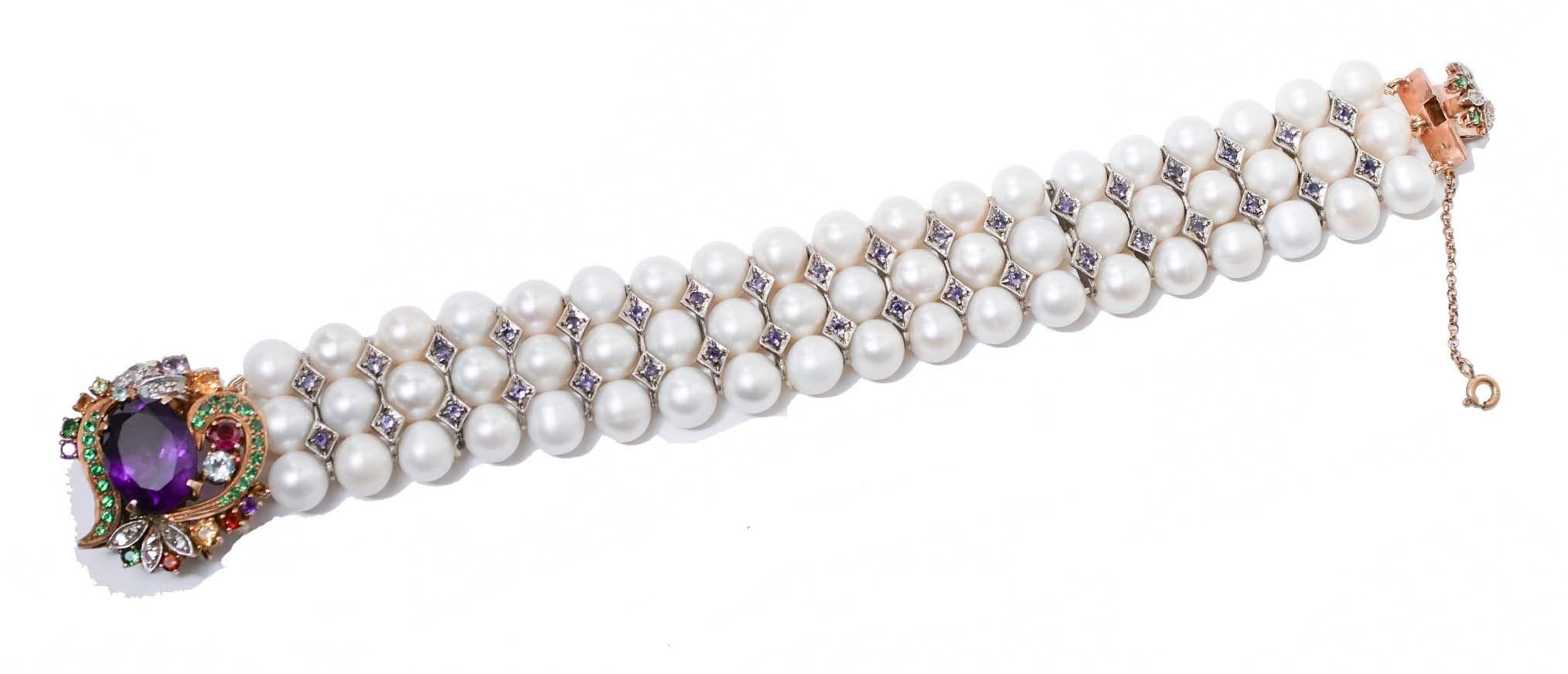 Amazing bracelet mounted with three strands of pearls and, between of them, structures in silver with iolite. As clasp, a structure in 14 kt rose gold and silver mounted with a central amethyst surrounded by topaz, tsavorite and diamonds.
This