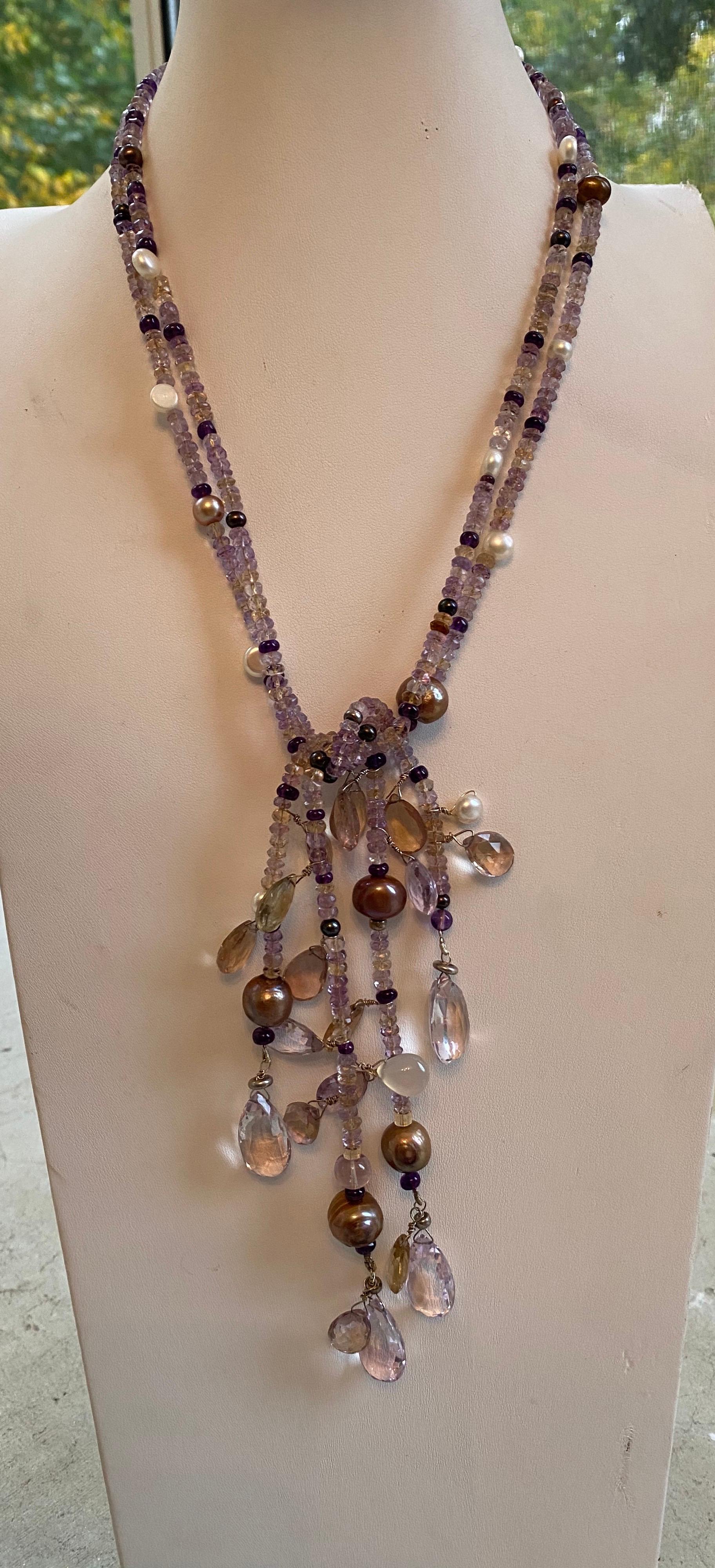 This is a lovely open lariat necklace adorned with Ametrine (Amethysts & Citrines) beads and Briolette Gemstones and White and Brown Freshwater Cultured Pearls throughout. Makes a bold statement of elegance and beauty to the wearer. There is only
