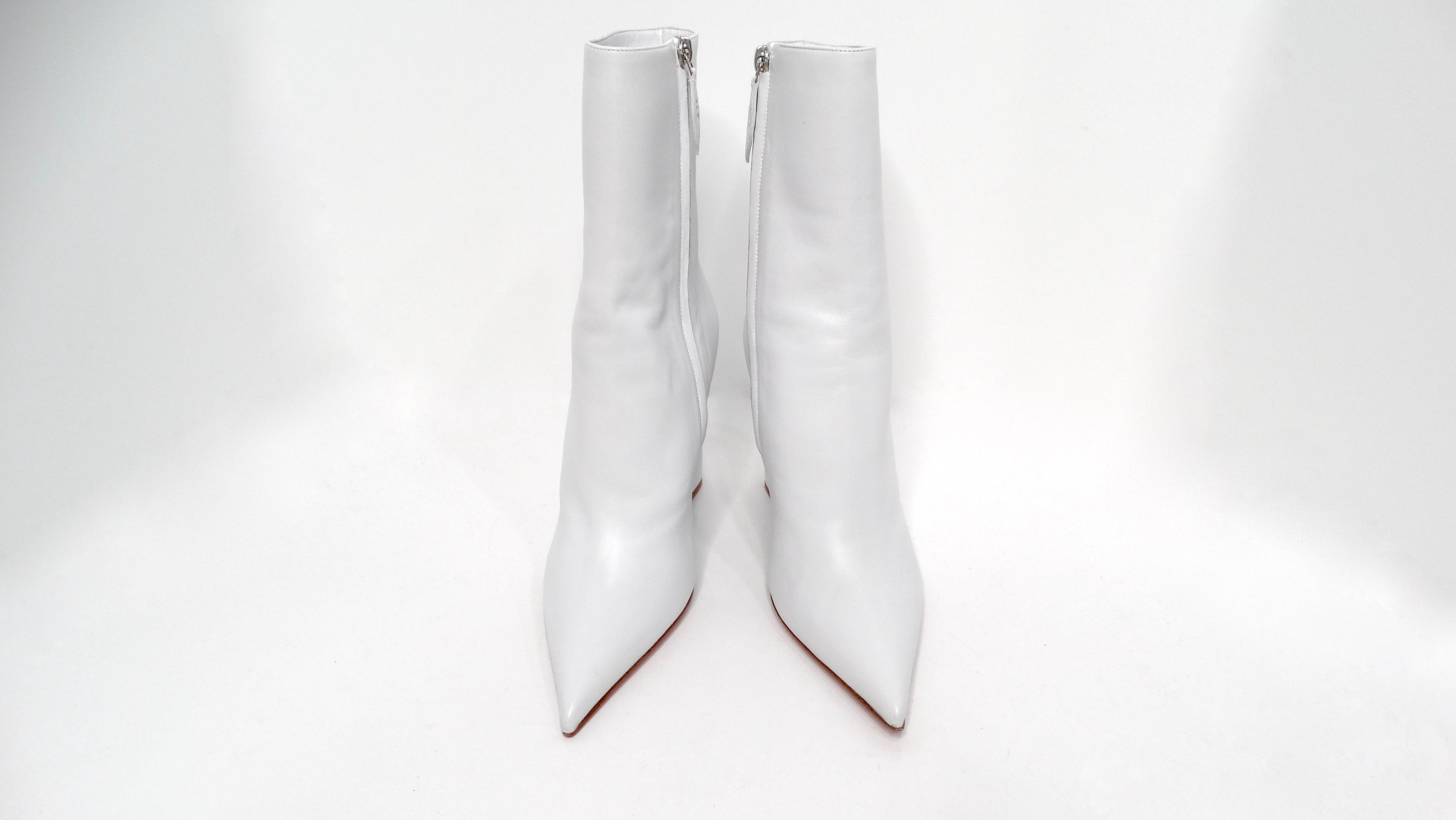 The Amina Muaddi Pernille White Leather Wedge Boots are a striking blend of modern sophistication and high-fashion flair. Crafted from exceptionally soft white leather, these boots feature a sleek, pointed toe silhouette that provides an elongated