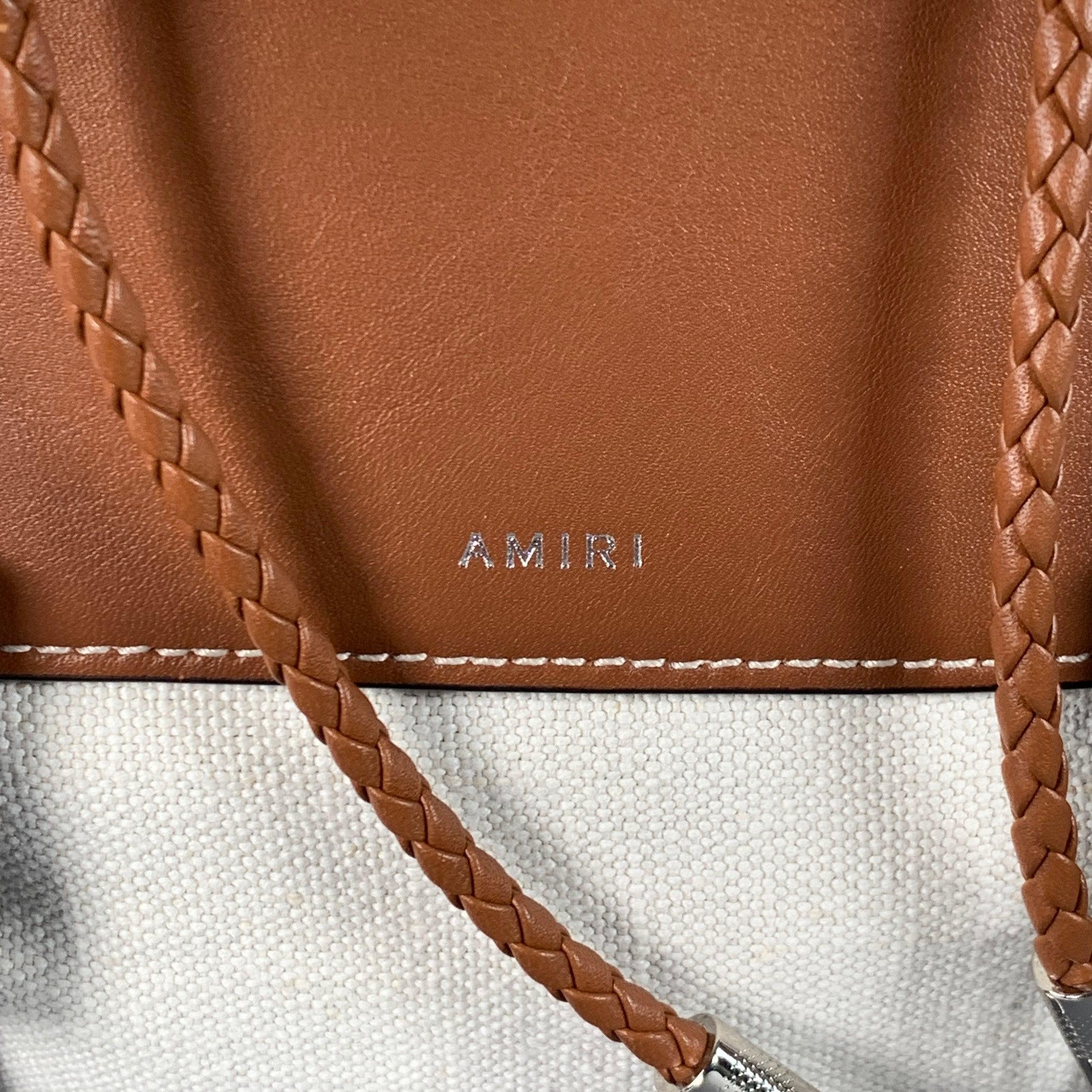 Zaino Amiri
in tela color crema con finiture in pelle marrone, con un ampio scomparto interno, una tasca esterna extra con doppia fibbia e una chiusura in corda intrecciata con fibbie. Viene fornito con sacchetto antipolvere. Made in Italy.Nuovo con