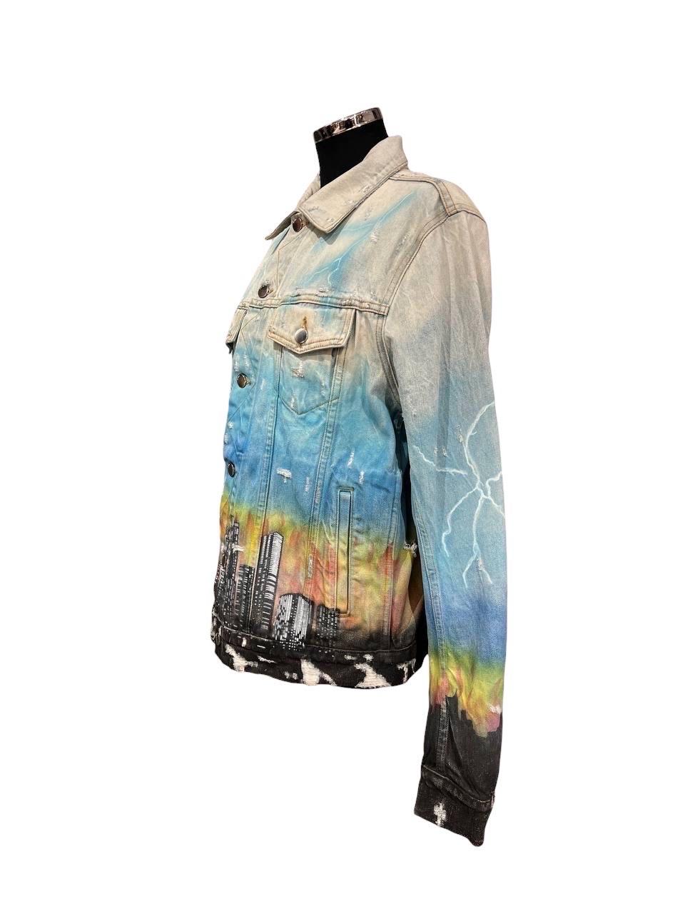 Manteau fabriqué par Amiri, réalisé en jean clair avec imprimé coloré, doté d'une doublure aux boutons et de deux poches latérales. La partie frontale, à hauteur de poitrine, présente deux tasses avec des boutons de fermeture. Taglia 52.

L'article
