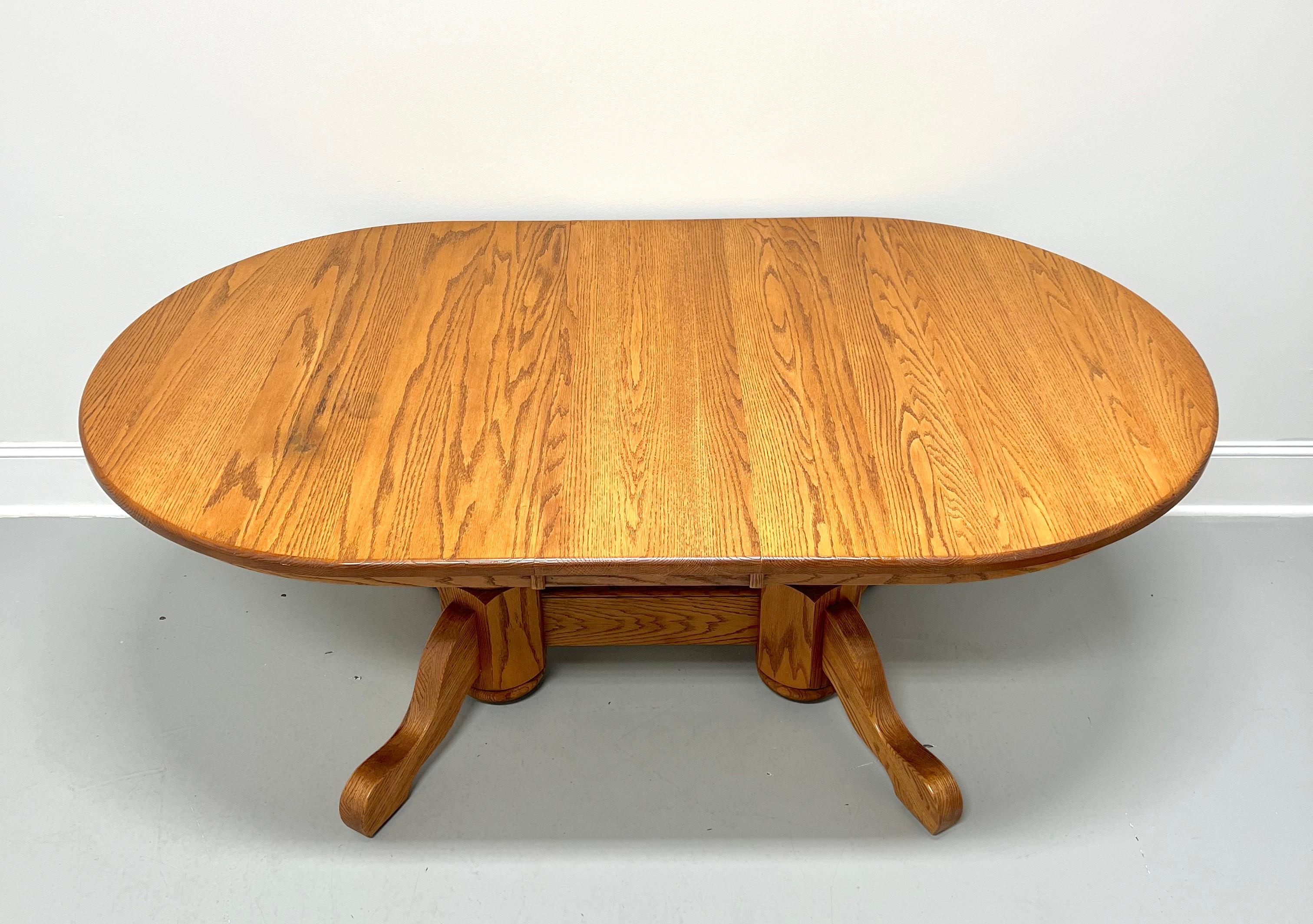 A handcrafted oblong dining table in the Rockford style by Amish craftsmen. Solid oak, oval shaped top with a bullnose edge, rounded smooth apron with accents, single trestle pedestal base with large turned supports joined by center turned spindles,