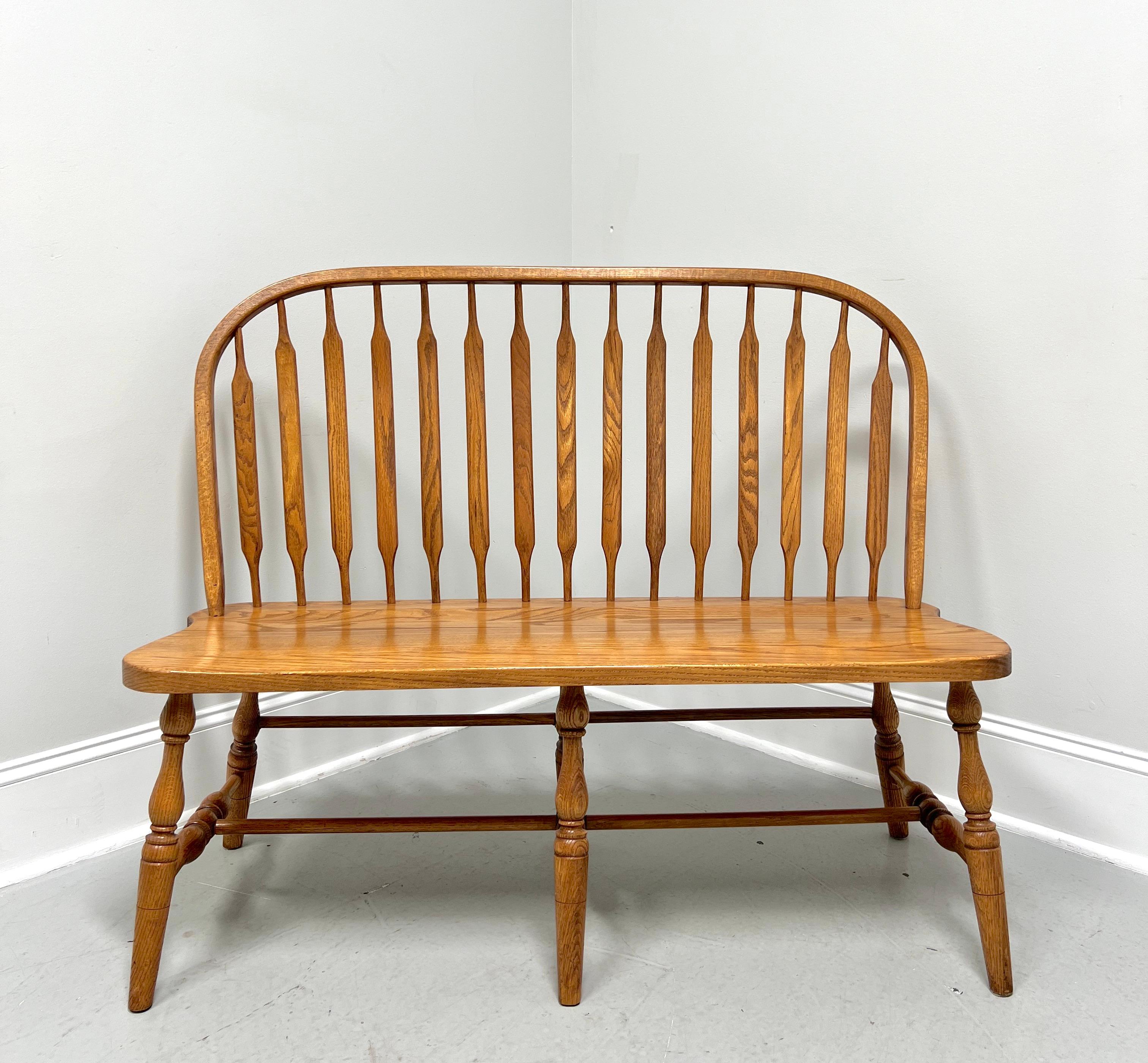 A handcrafted Windsor bench in the Rockford style by Amish craftsmen. Solid oak, bowback, cattail spindles, solid seat, turned legs, turned side & middle stretchers, and rounded center & back stretchers.  Made in the USA, in the late 20th