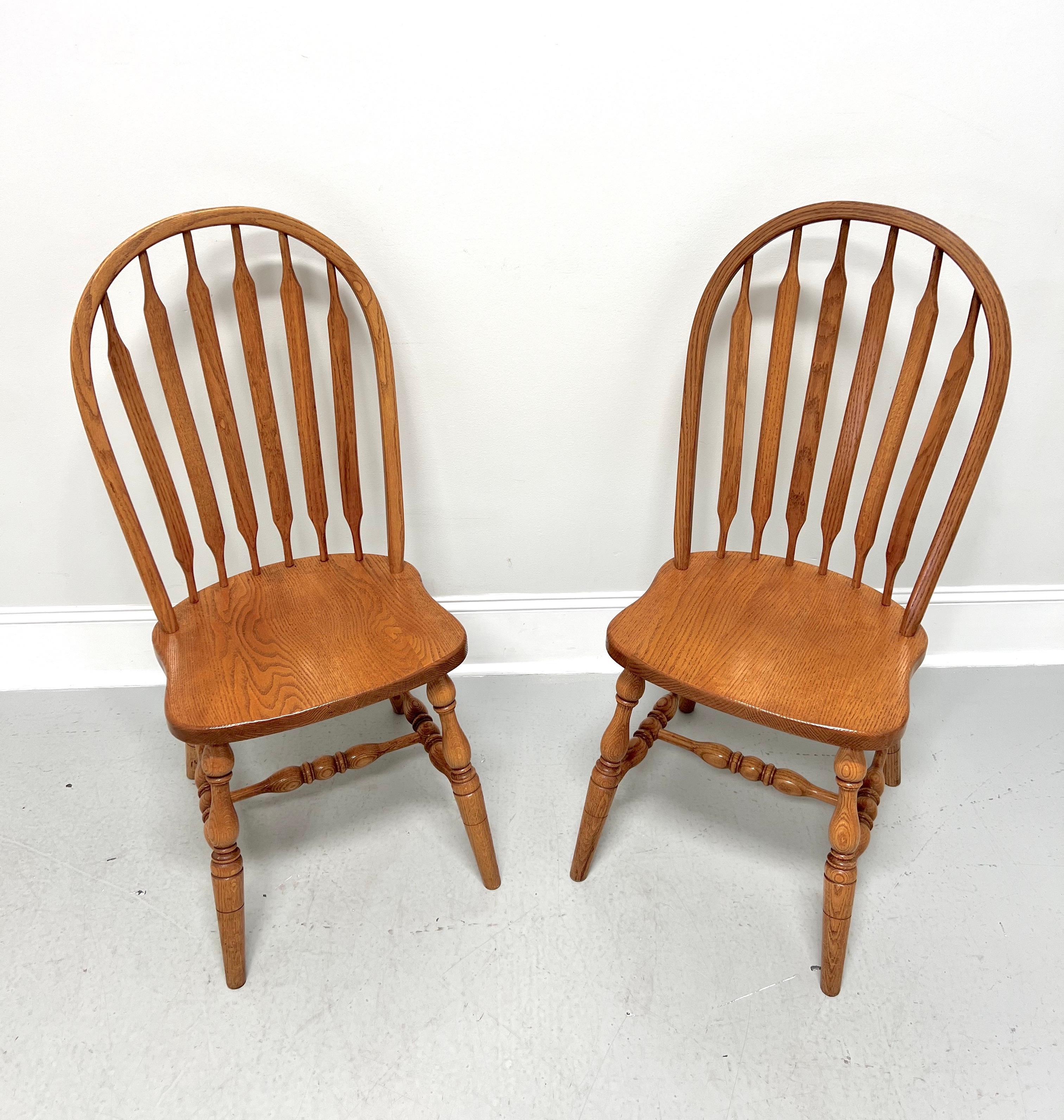 A pair of handcrafted Windsor dining side chairs in the Rockford style by Amish craftsmen. Solid oak, bowback, cattail spindles, solid seat, turned legs, and turned stretchers.  Made in the USA, in the late 20th Century.
 
Measures:  18w 23d 40h,
