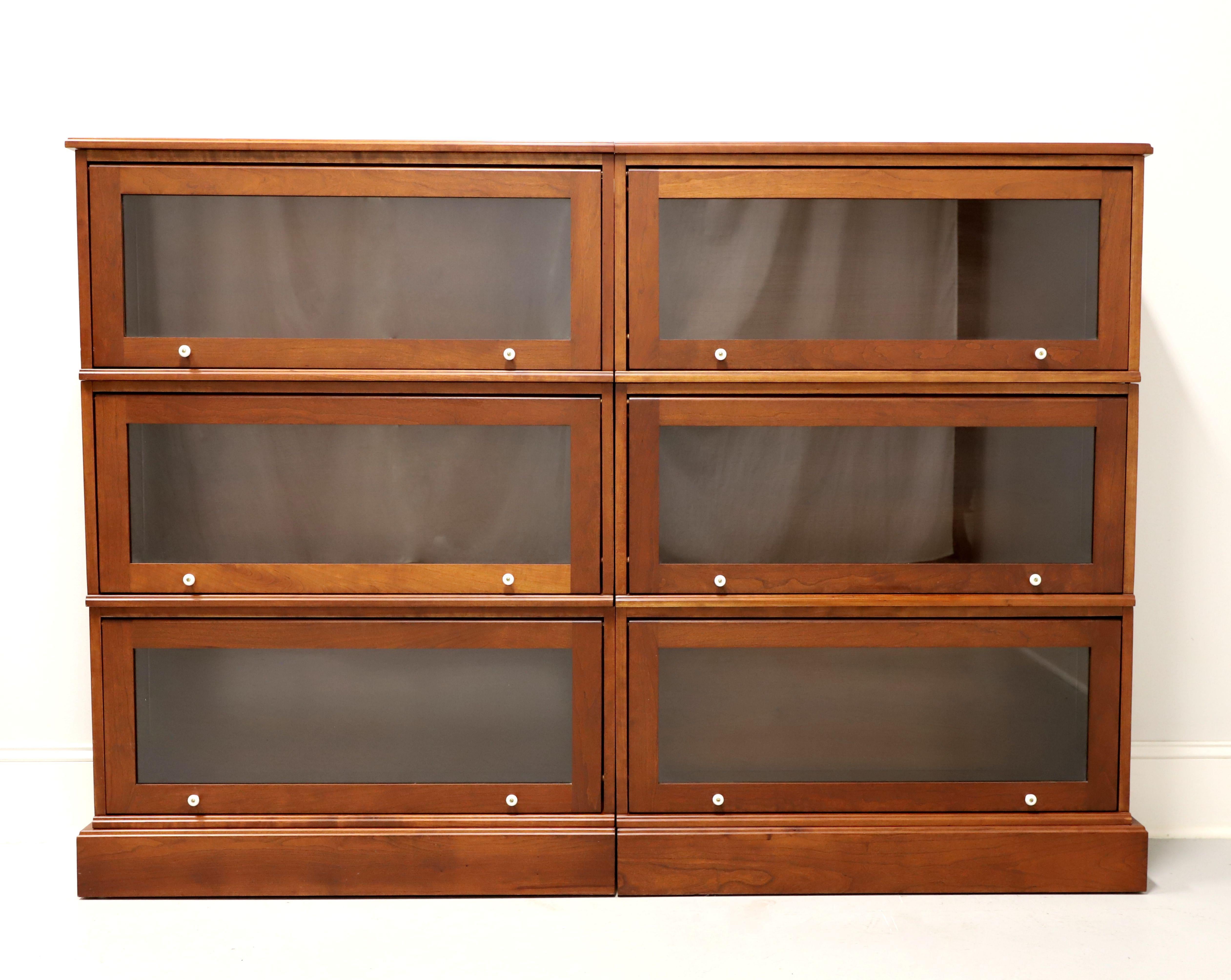 A matched pair of Arts & Crafts style stacking barrister bookcases by Amish craftsmen. Handcrafted of solid cherry wood with white porcelain knobs, bevel edge to front & one side of top, and a solid base with one side being flush & the other side