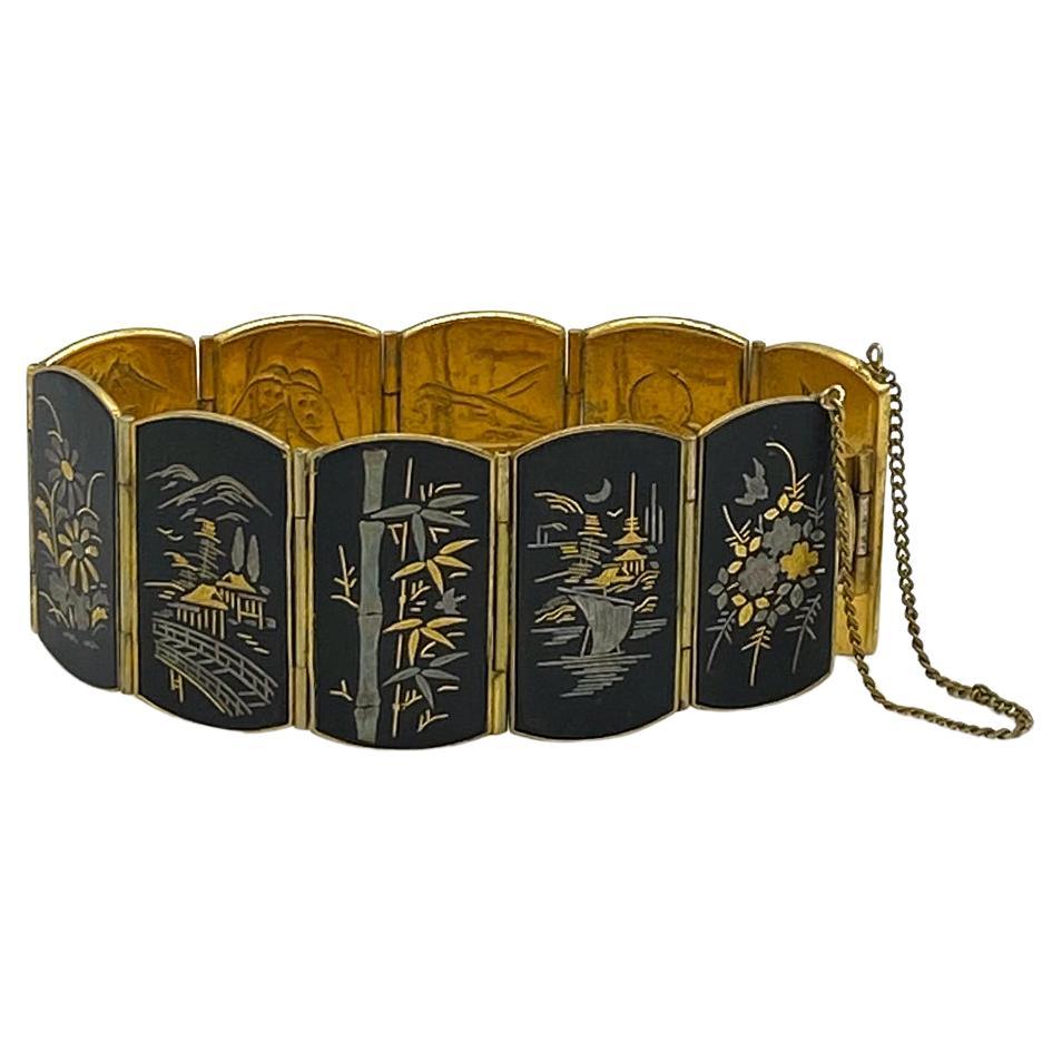 Se trata de una pulsera de damasquinado Amita Japan. Tiene diez paneles abatibles de 0,63 x 1,25 pulgadas. Cada escena muestra una bella imagen japonesa que incluye montañas, bambú, flores y pájaros. La cara interior de la pulsera también está