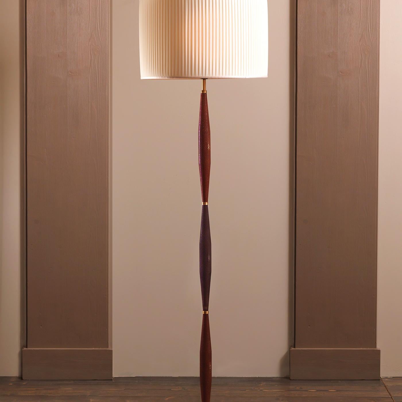Conçu par Ciarmoli Queda Studio, ce lampadaire sophistiqué est un exercice d'élégance intemporelle. La tige est constituée d'éléments doublement effilés recouverts de peau de galuchat et marqués en haut et en bas par des accents en laiton. Il repose