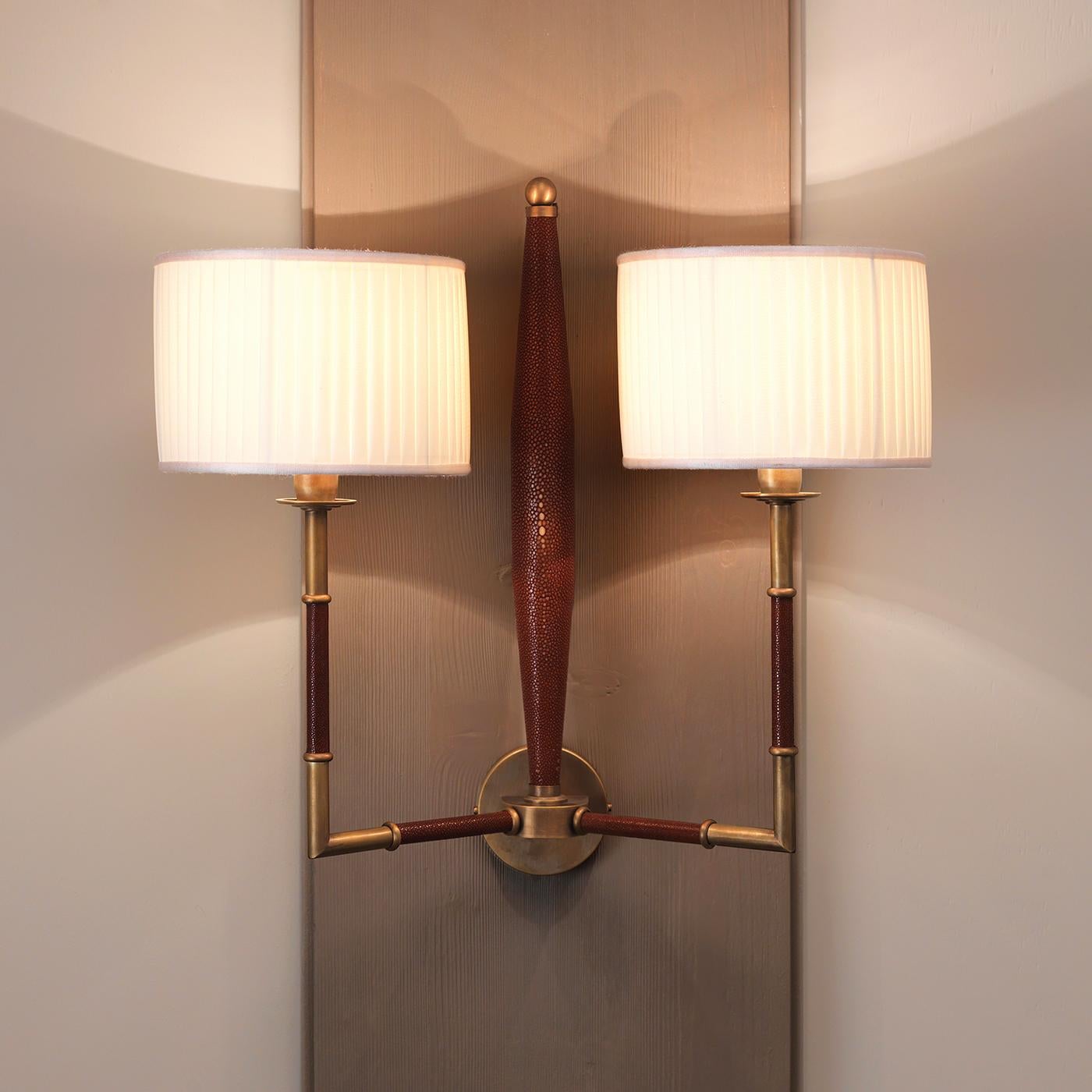 A striking combination of stunning materials and textures enlivens the rigorous silhouette of this elegant sconce designed by Ciarmoli Queda Studio. The brass structure comprises a central circle supporting two functional arms and a decorative one