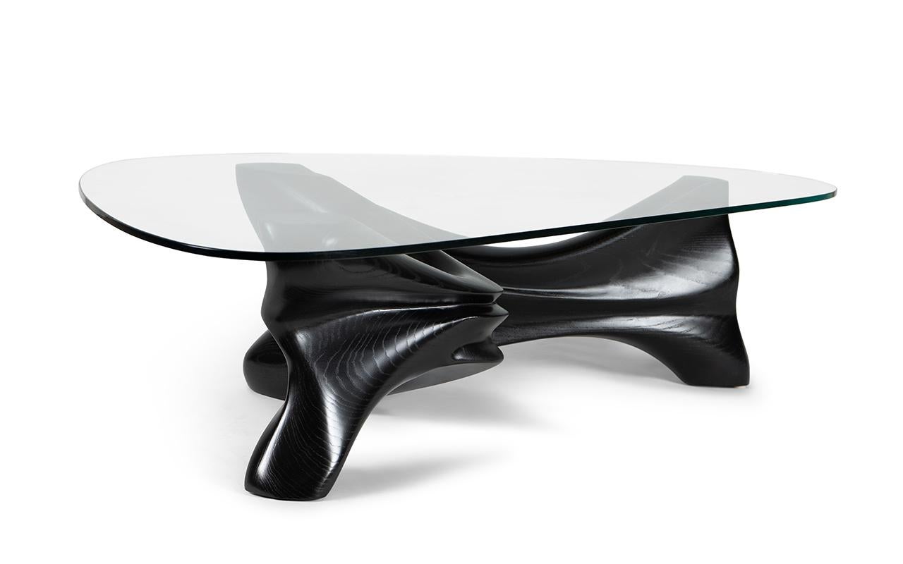 Der Couchtisch Zen ist ein atemberaubendes Möbelstück, das jedem Zuhause einen Hauch von moderner Eleganz verleiht. Mit seiner dreieckigen Glasplatte und seiner geschwungenen Form ähnelt er einem Stoff, der in der Luft anmutig geriffelt und dann mit