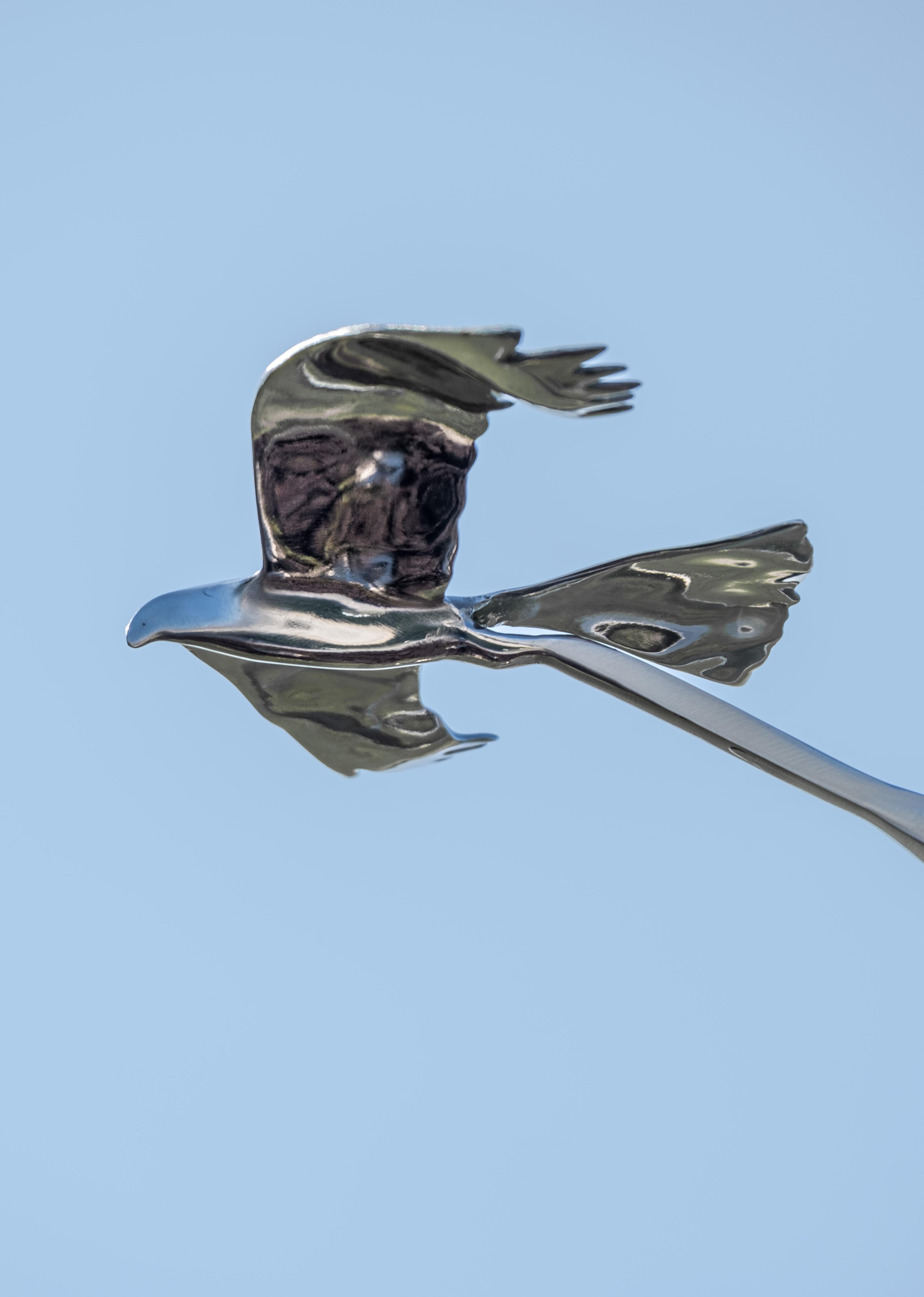 The graceful flight of two birds is captured in this stunningly elegant contemporary sculpture by Amos Robinson. The American artist hand forged this kinetic piece from stainless steel. Two birds-wings outstretched, (each birds wingspan is 12”), are