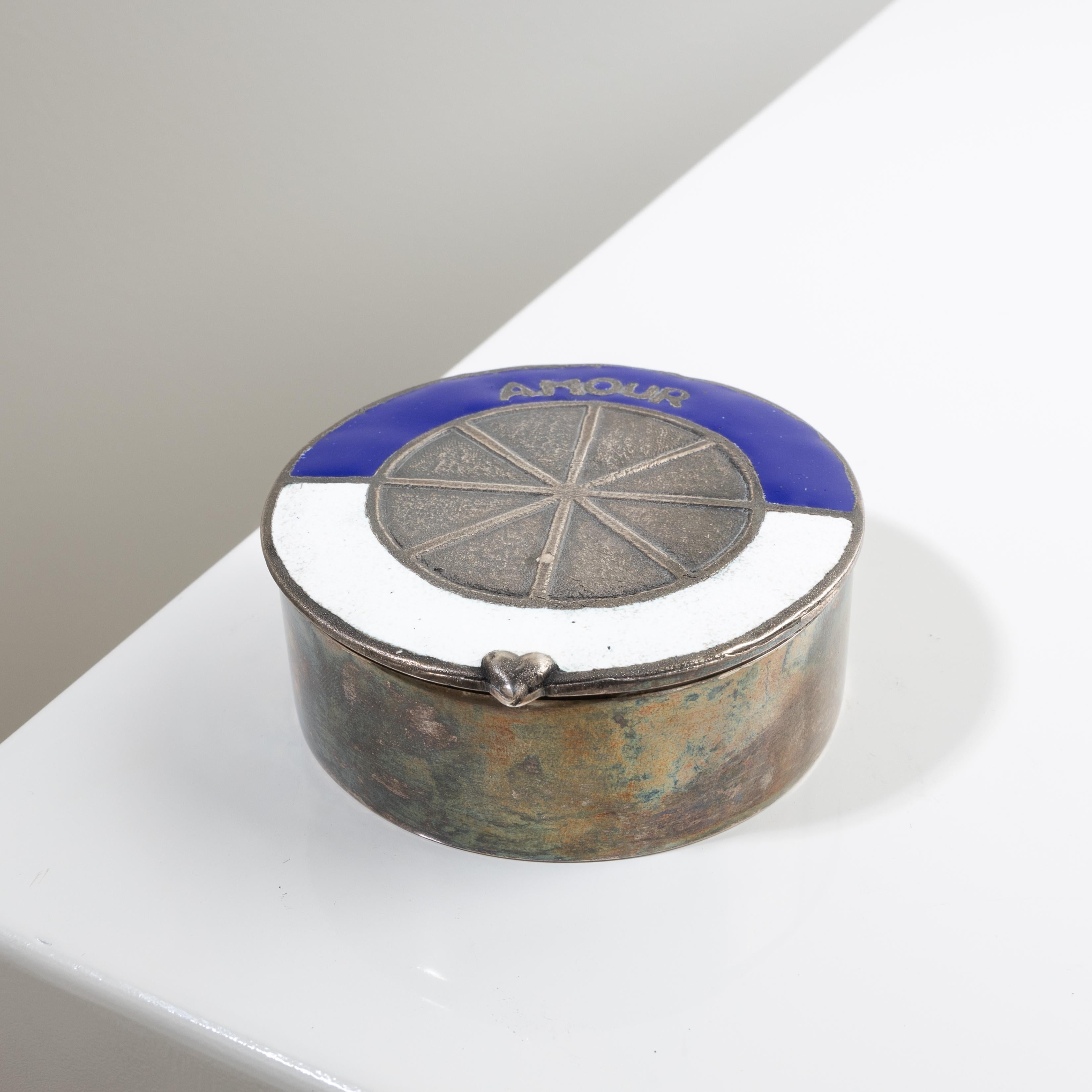 Amour roi de ton coeur (Amor rey de tu corazón) de Line Vautrin , Caja de Bronce Plateada.
Caja de bronce plateado con tapa realzada con una decoración que representa una rueda bicolor, la parte superior esmaltada en azul y la inferior esmaltada en