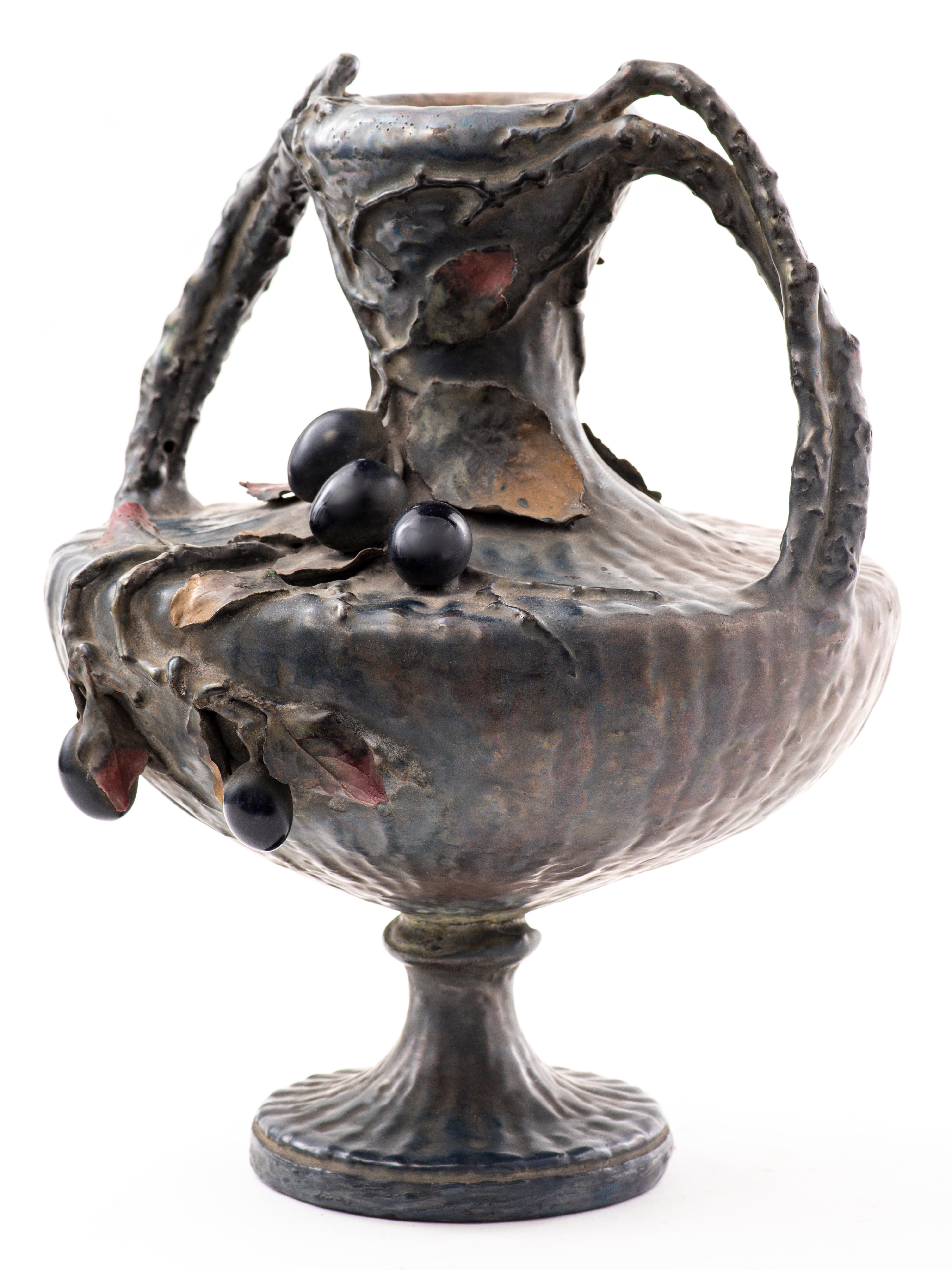 Amphora Austrian Art Nouveau semi-iridescent ceramic two-handled vase decorated with hanging grape cluster and vines and leaves. Marked and numbered on bottom. Dimensions: 13.5