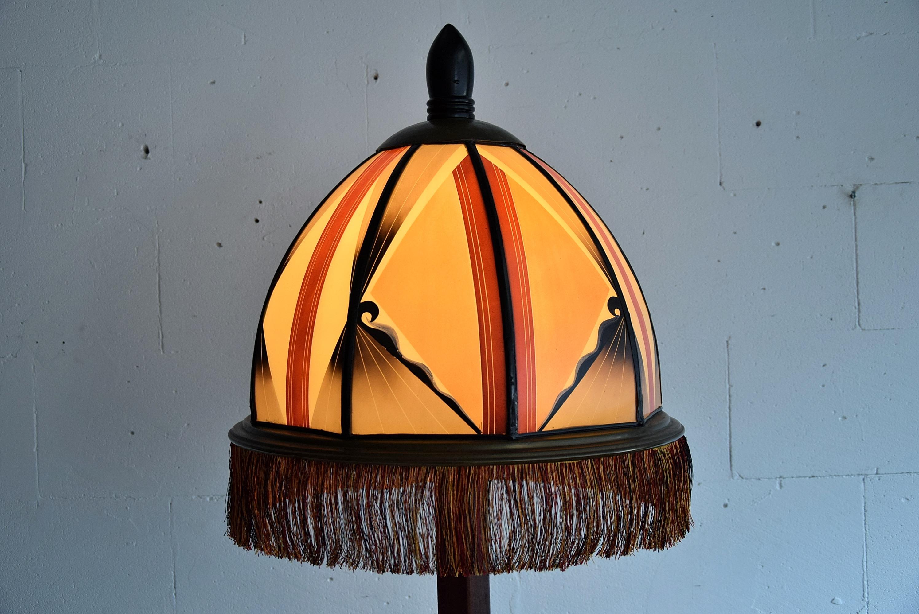 Beautiful Art Deco Amsterdam School floor lamp made in the Netherlands in the 1920s. The frame of this rare and impressive work of art is made of solid mahogany decorated with Macassar Ebony details and feet. The burned painted glass shade, in