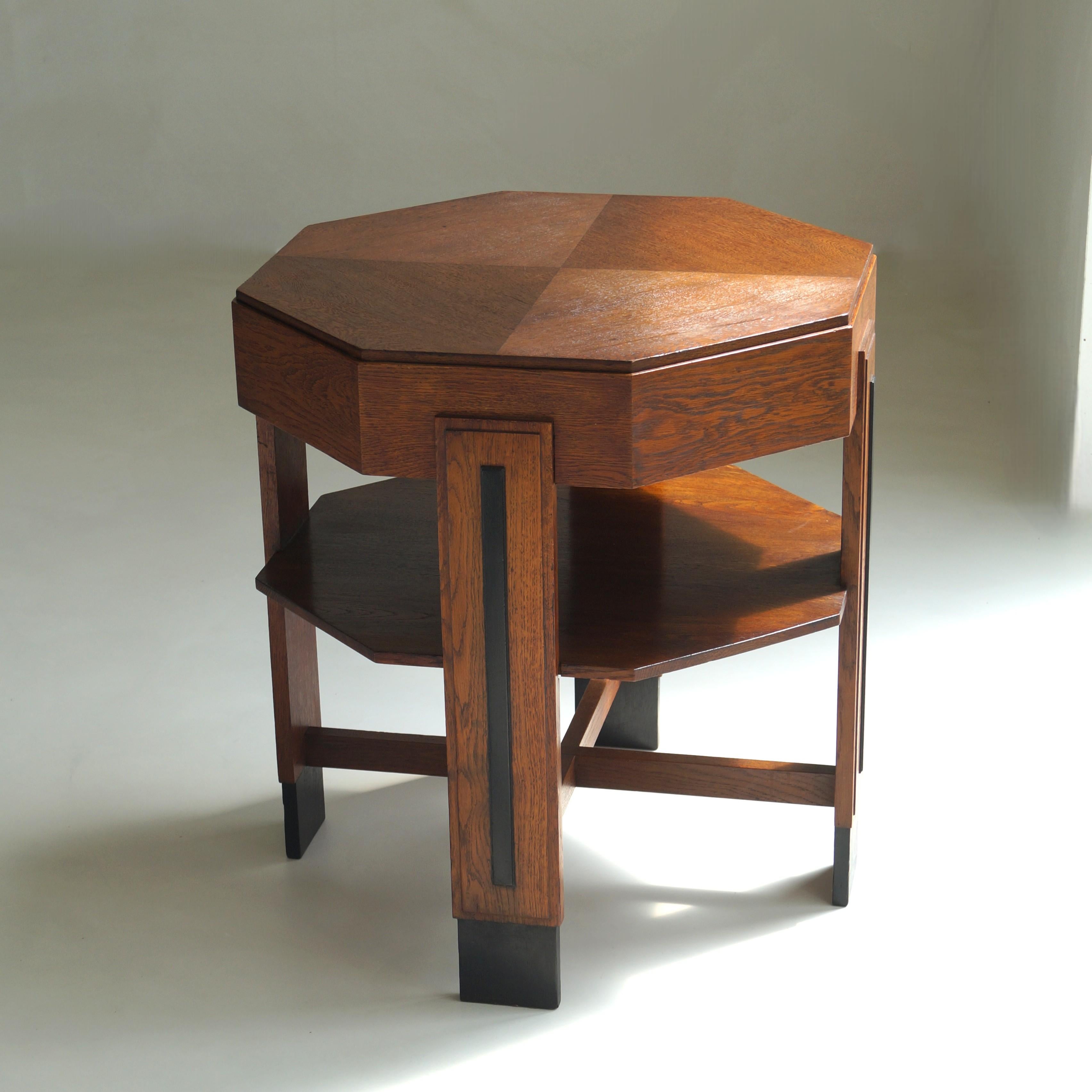 An impressive Dutch Art Deco side table in oak and oak veneer, dating from the 1920s and exemplary of Amsterdam School design. This geometric piece features an octagonal top with quartered oak veneer, enhancing the play of light. Beneath, a lower