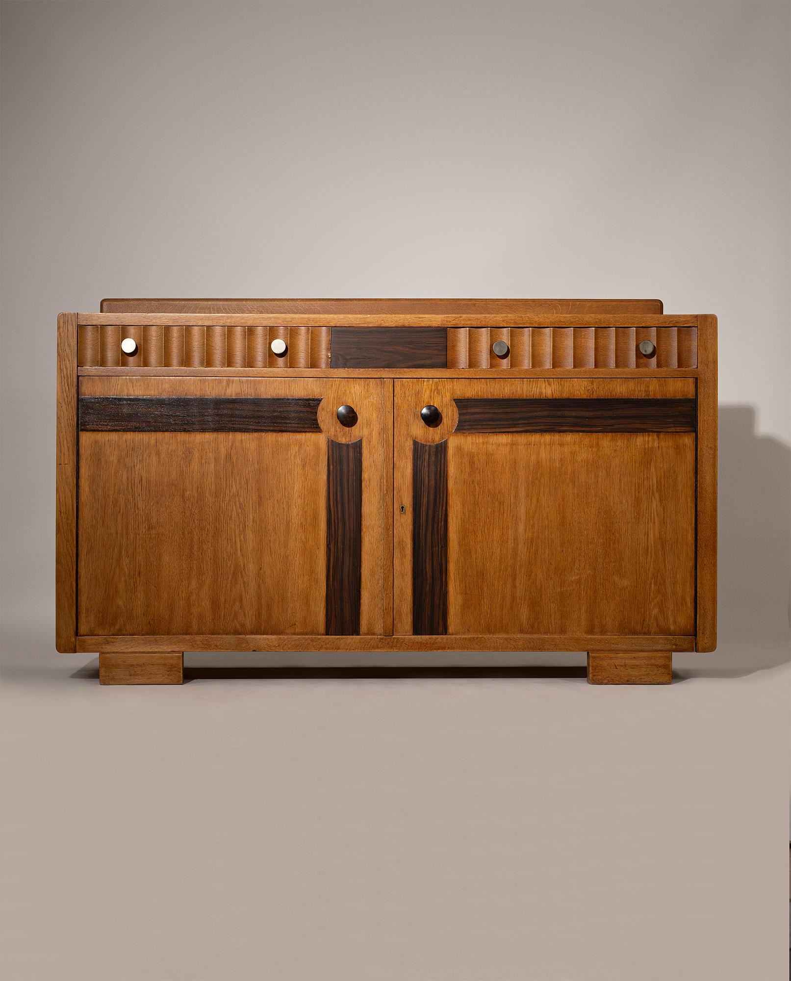 Risalente alla fine degli anni '20 e all'inizio degli anni '30, questa credenza della Scuola di Amsterdam incarna la miscela di geometria audace e maestria espressiva del movimento. Realizzato in rovere massiccio, presenta pannelli scultorei