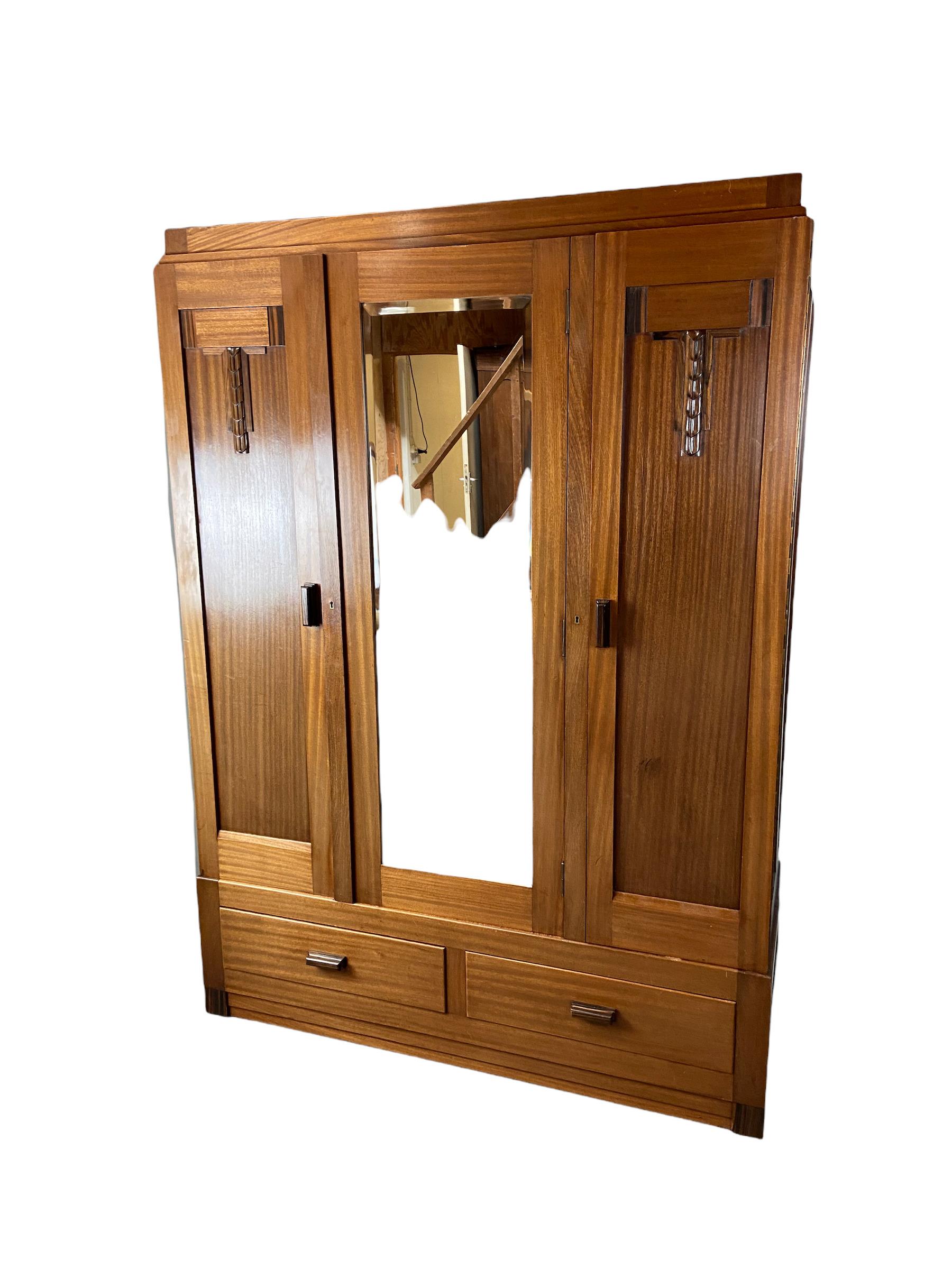 Amsterdam School wardrobe made of mahogany wood with coromandel accents and massive oak shelves and a faceted mirror. Dutch design from the 1920s. This object is in a good condition but there are no keys.