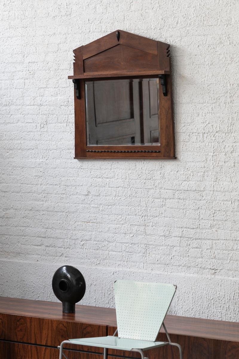 Mirror designed and made in the period of the Amsterdamse School, 1930s. The frame of the faceted mirror is made of dark stained wood with ornamented sides. This Art Deco piece is in good condition.