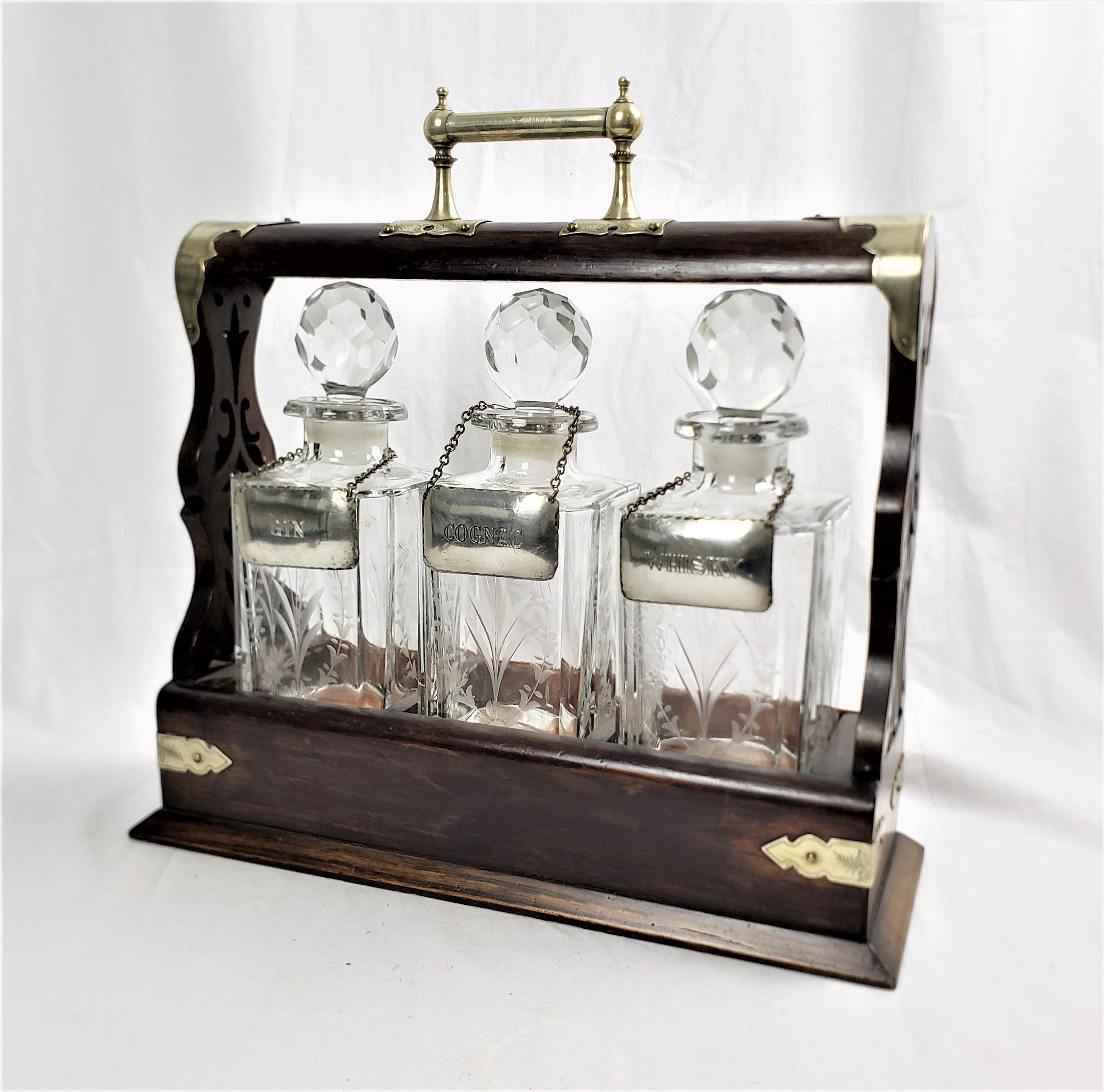 This antique tantalus set is unsigned, but presumed to have originated from England and date to approximately 1900 and done in the period Edwardian style. The case is composed of oak with silver or nickel plated mounts. The squared bottles are