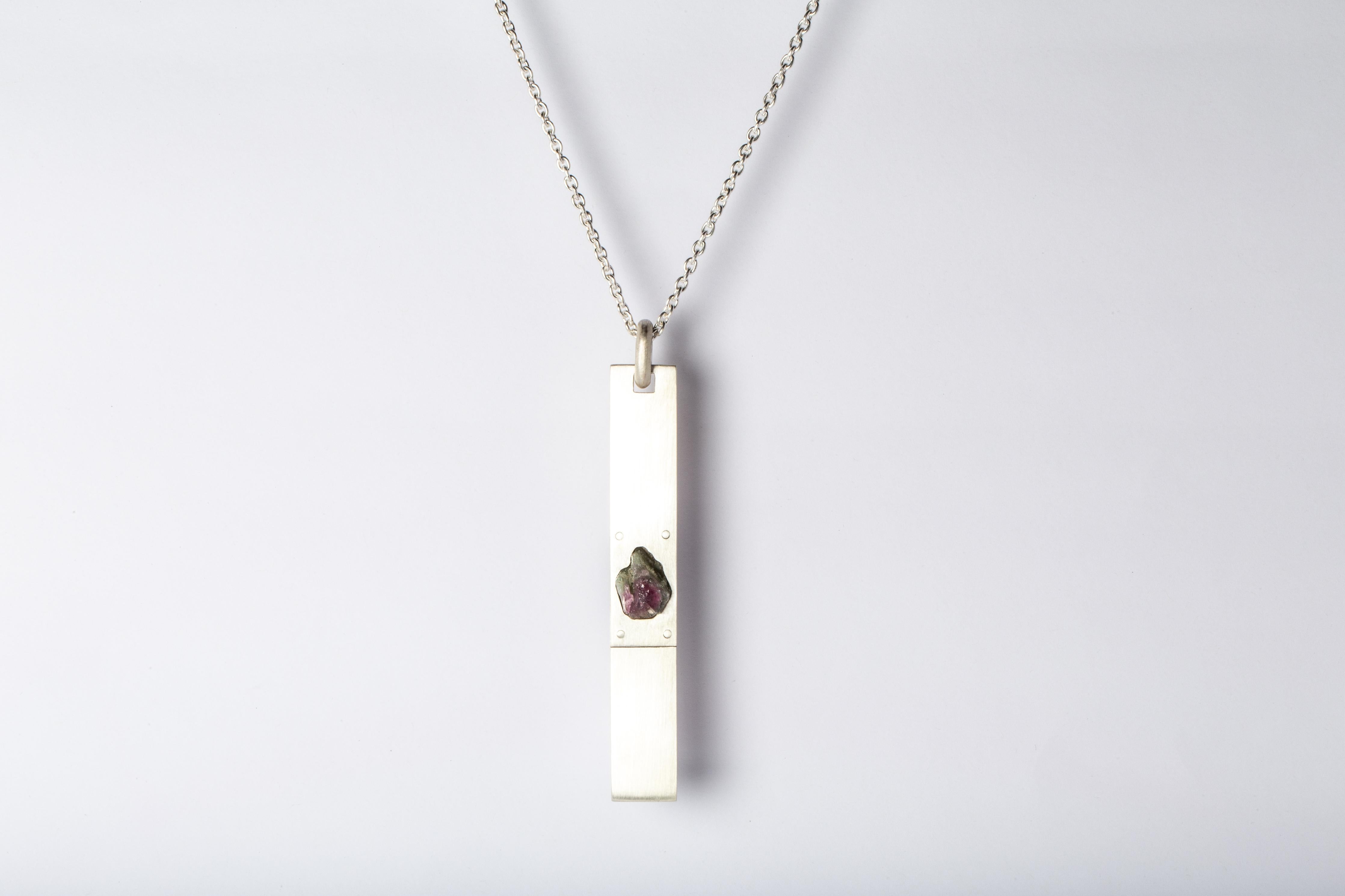 Necklace made in matte sterling silver and a rough of elbaite, a green-pink tourmaline color. The Amulet series seeks to encapsulate the energy of a mineral element(s). This family is a branch from the Talisman family and seeks to further explore