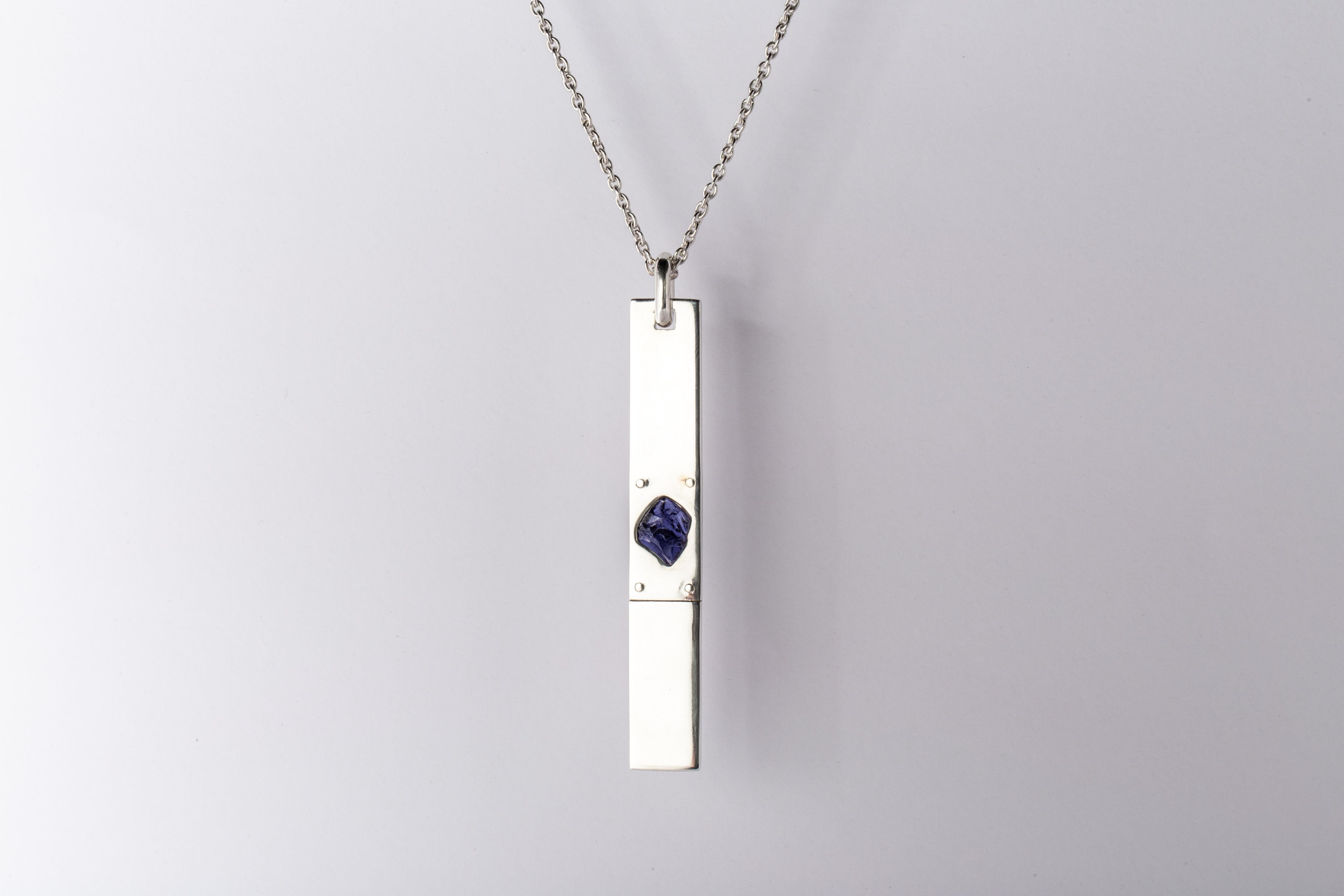 Pendant necklace in polished sterling silver and a slab of rough iolite in purple color. The Amulet series seeks to encapsulate the energy of a mineral element(s). This family is a branch from the Talisman family and seeks to further explore the