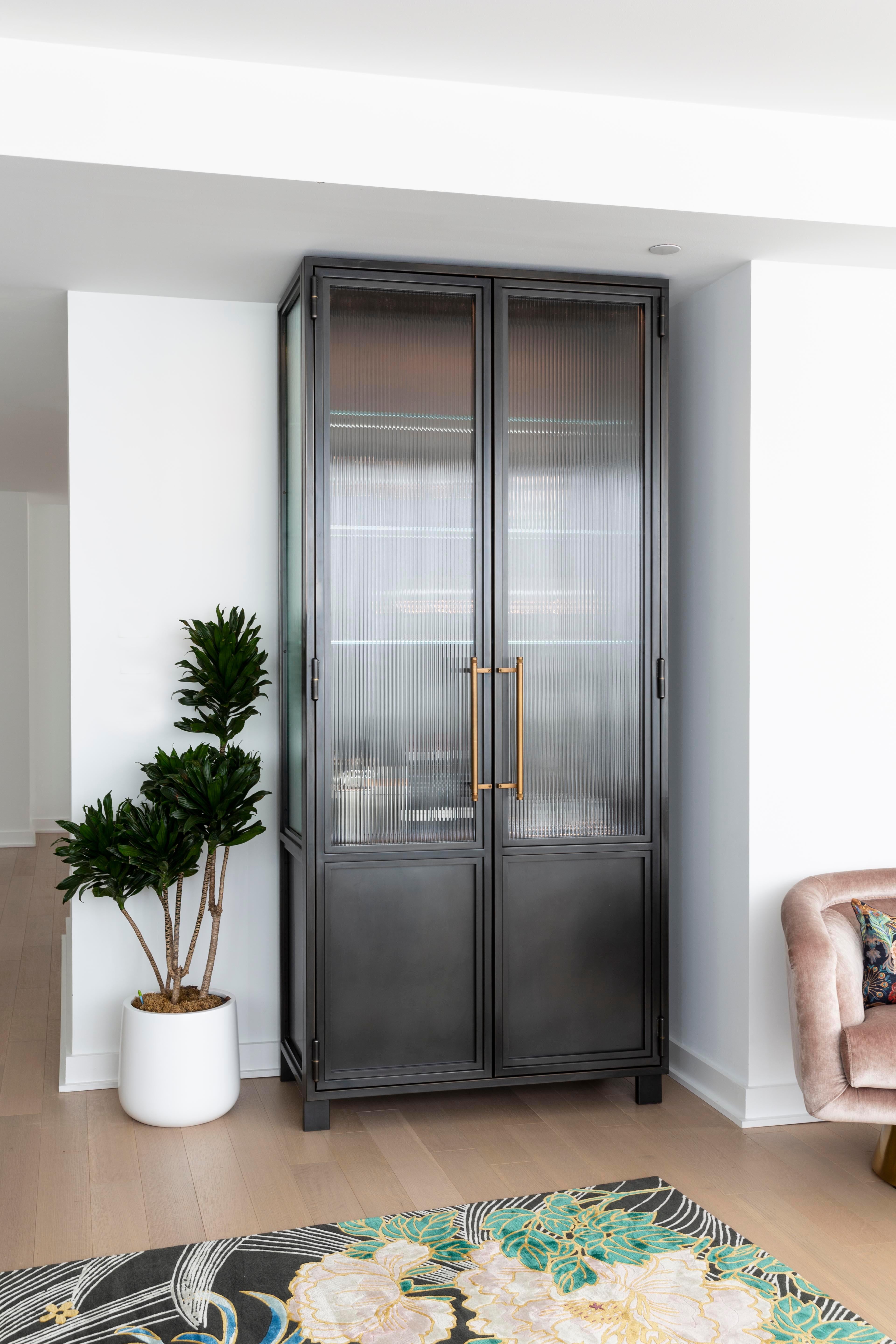 These versatile industrial-inspired cabinets bring strength and character to any space with their over-sized blackened steel and glass doors, framework and custom machined brass pulls. The interior of each cabinet offers truly flexible storage