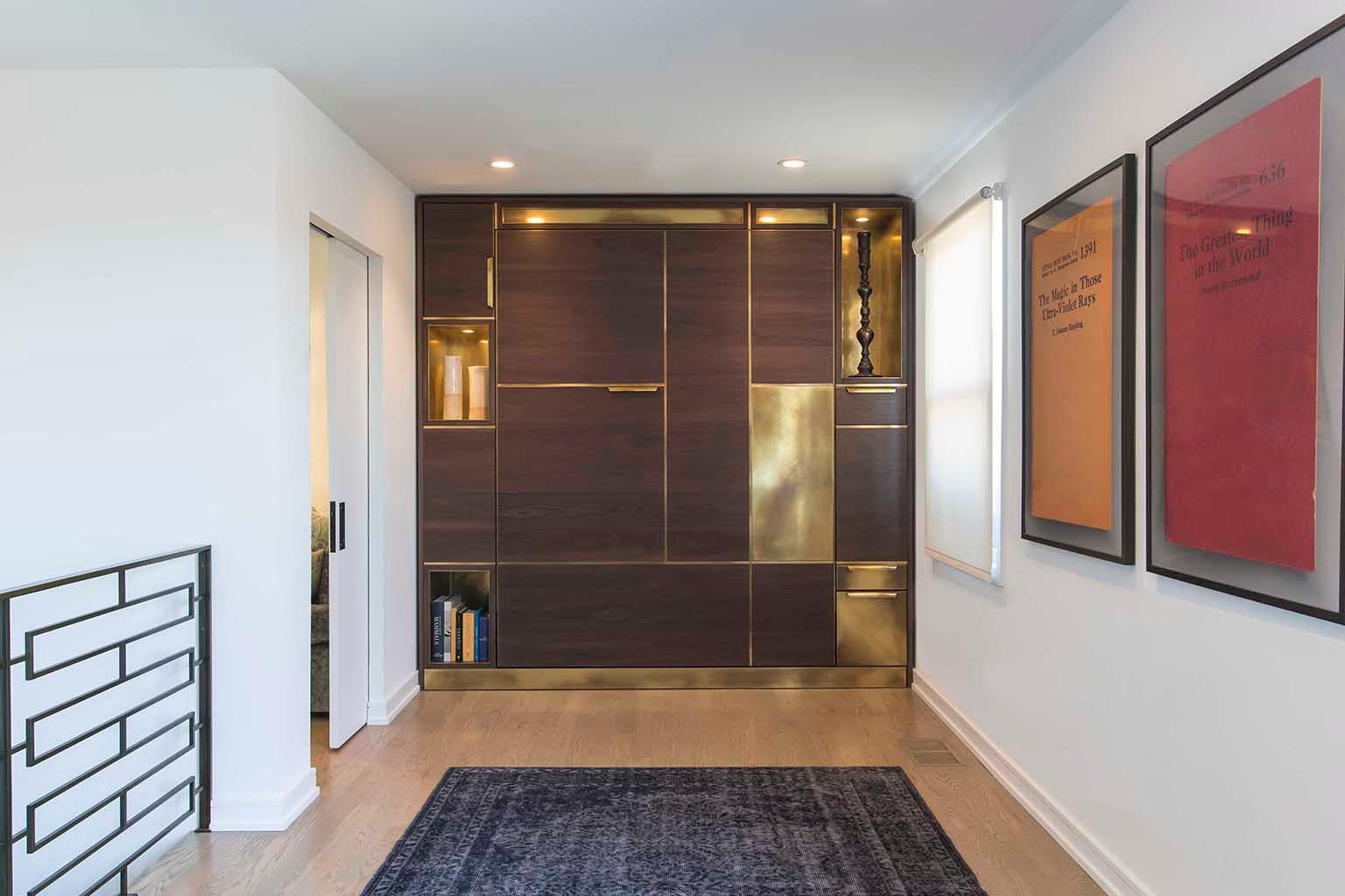 Designed to feel like a built-in piece of millwork Amuneal’s Murphy bed conceals a queen-sized mattress behind panels of silvered walnut with warm brass inlays. With the bed closed, the walnut and brass panels work with brass clad cubbies and
