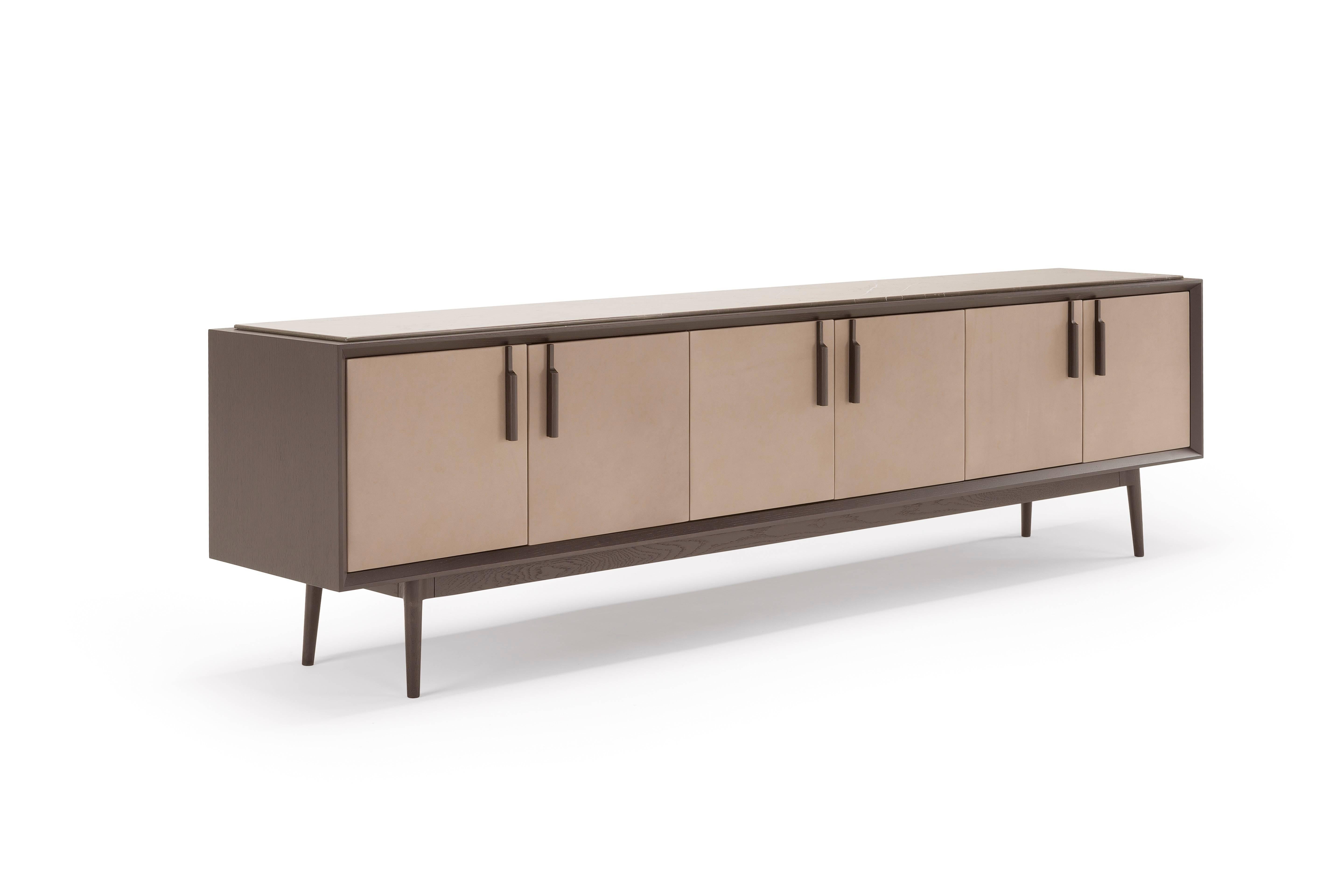 Theo 

Theo is a modern take on a traditional furniture piece: the sideboard. The elegant wooden container in dark oak is enriched by a refined detail: the leather upholstery of the doors, themselves enhanced by the slender oak handles. The base