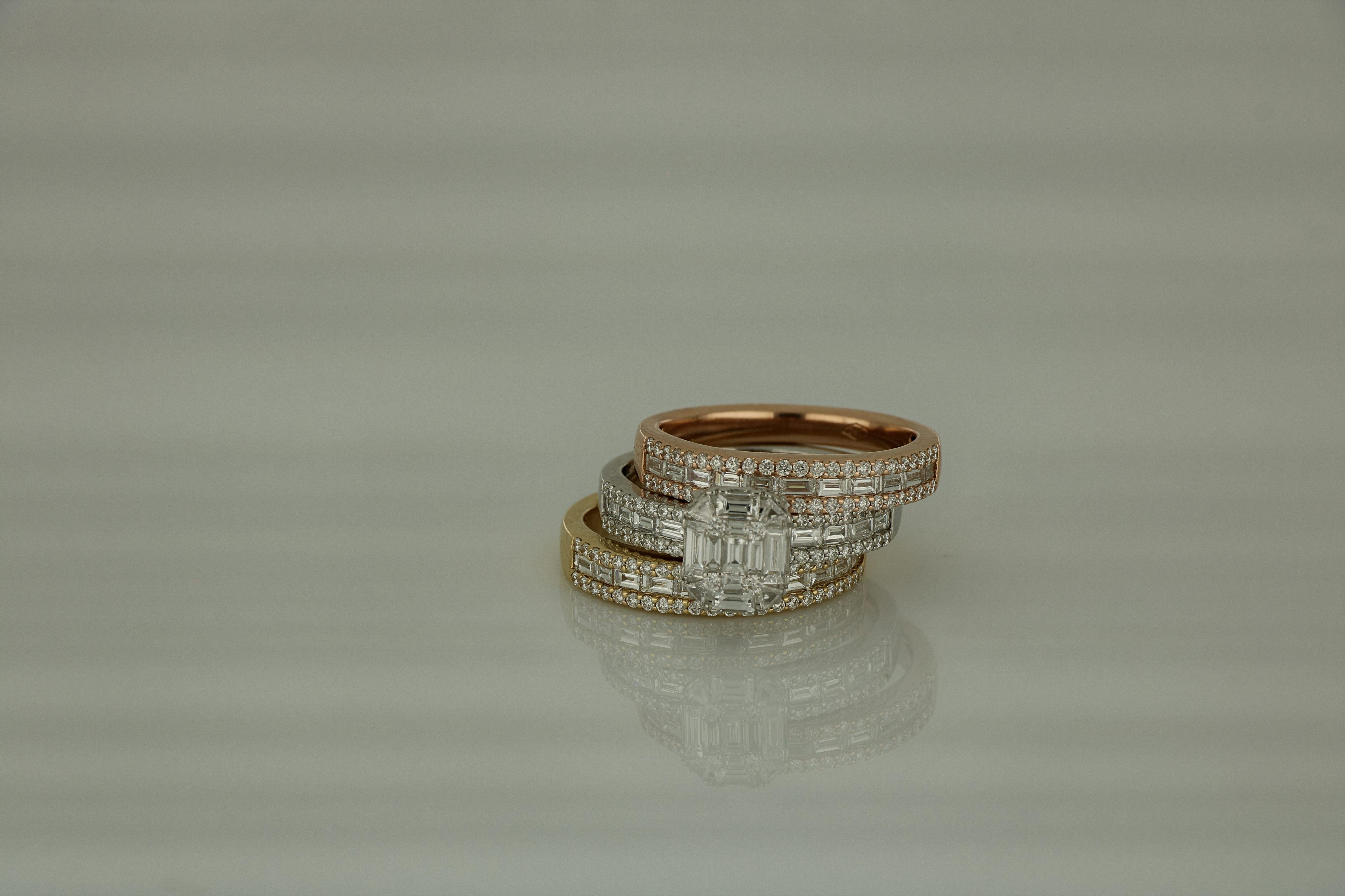 Sleek rows of small Baguette Diamonds grouped by a master round and emerald diamond frame three faceted rose ,white and yellow gold bands that rotate independently of each other ,catching and reflecting the light , in this graphic Amwaj Signature