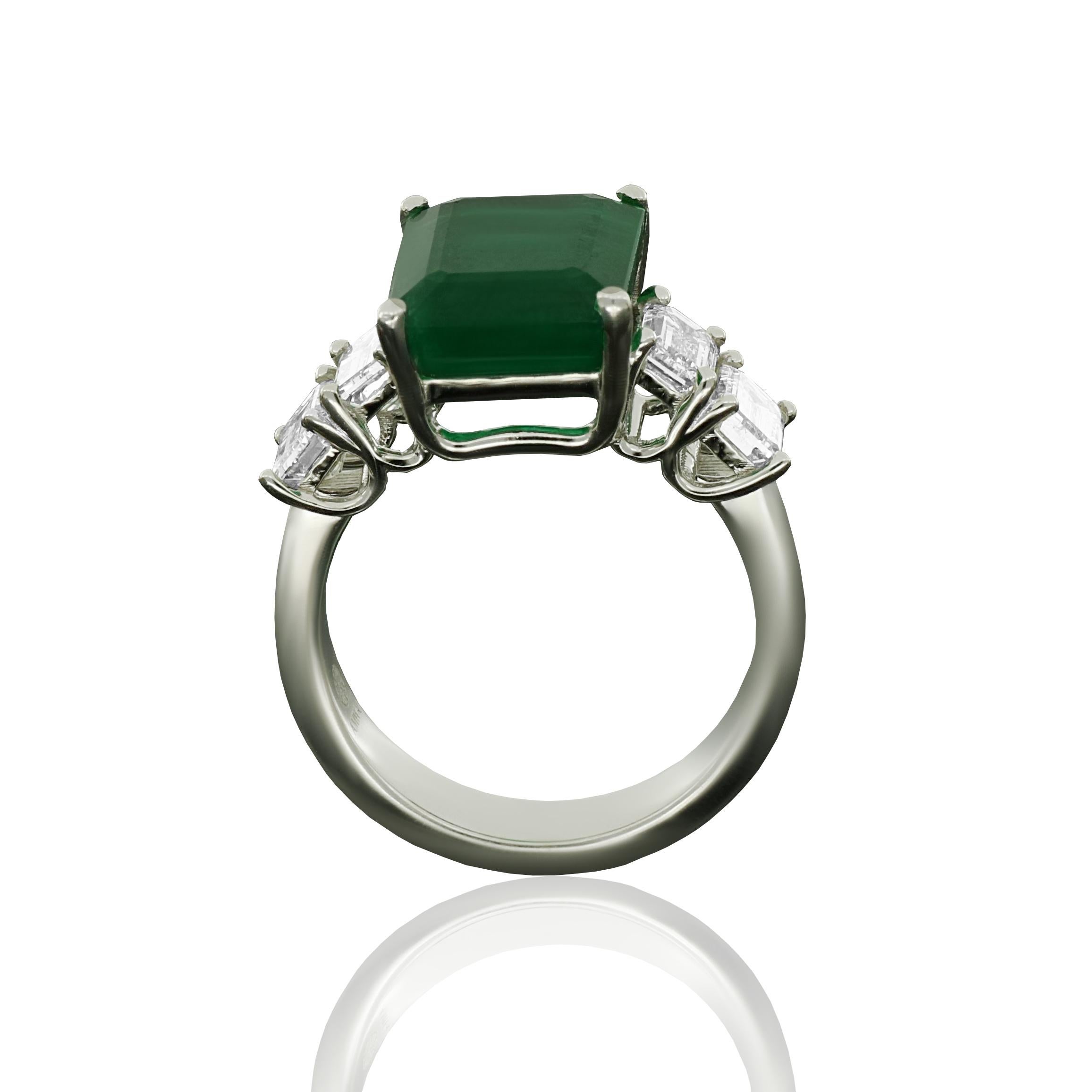 A contemporary 18 karat white gold ring featuring emerald cut white diamonds with a total weight of 1.59 carats, centralized by 5.53 carat emerald cut emerald. 
Diamonds (Total Carat Weight: 1.59 ct)
18 Karat White Gold
Ring Size: 52, 12, 6
]Diamond