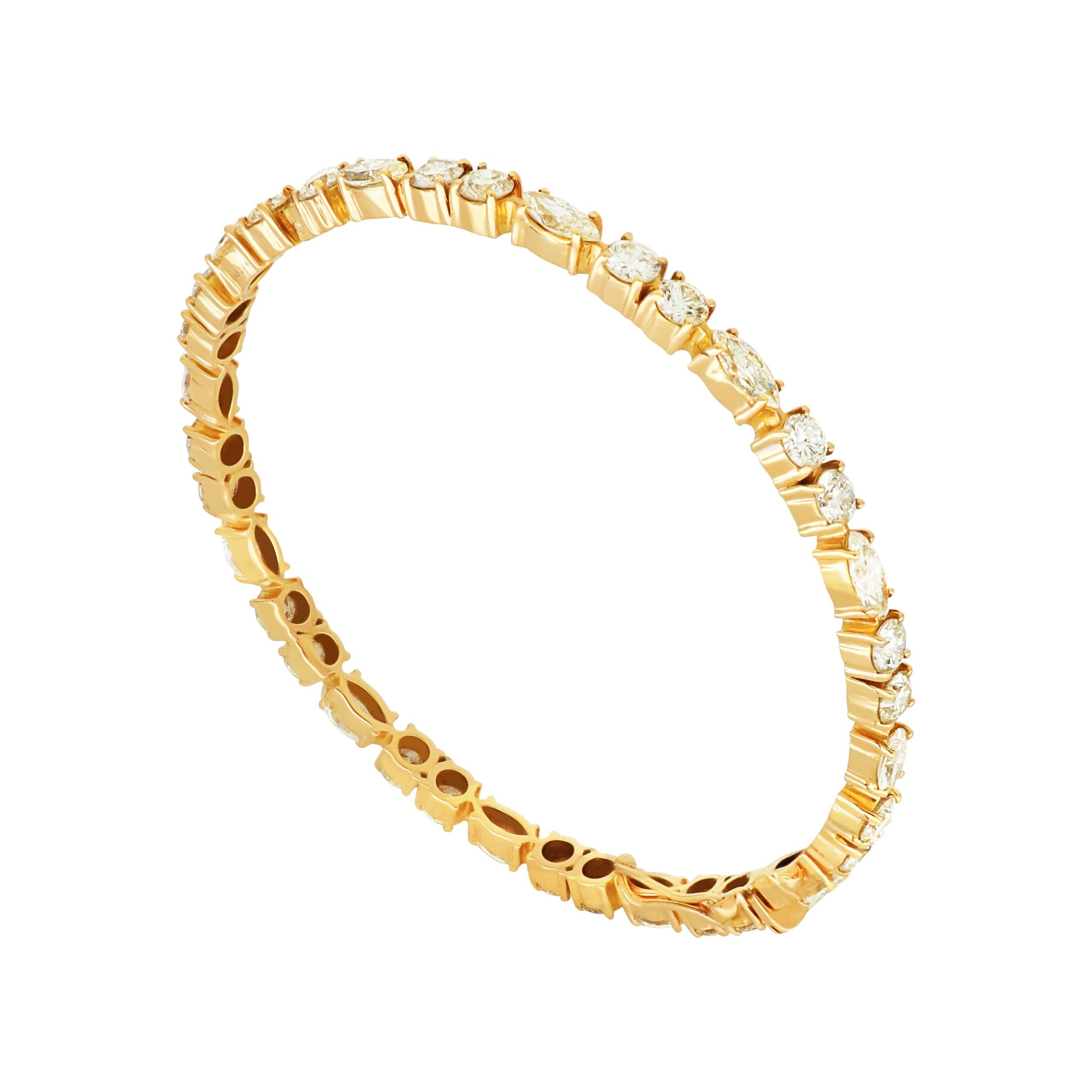 A contemporary line 18 karat yellow gold bangle featuring the round cut diamonds, punctuated by marquise diamonds to form a seamless stream of scintillation around the wrist. 
Diamonds (Total Carat Weight: 7.48 ct) 
18 Karat Yellow Gold
Bangle Size: