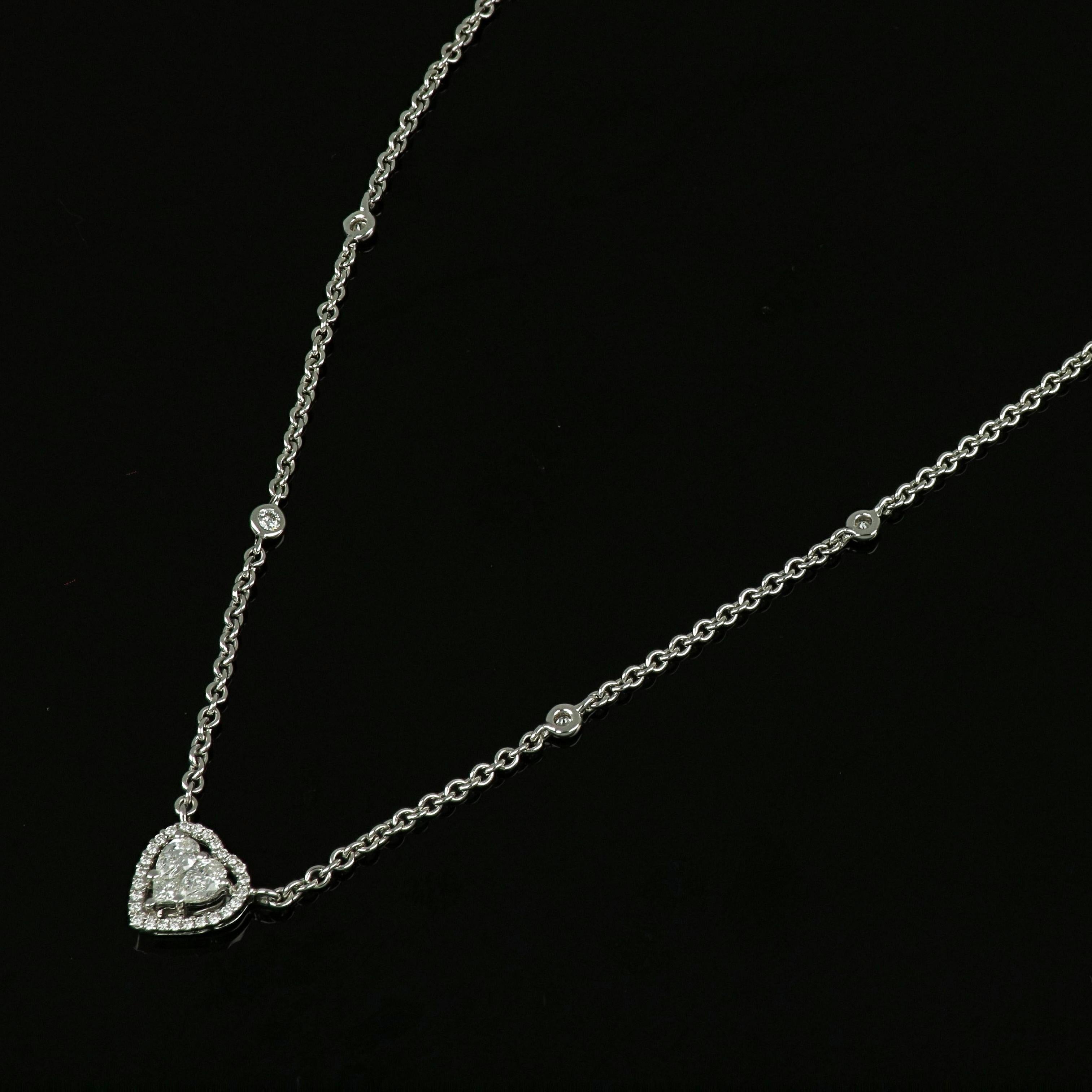 This 18 karat white gold heart shaped diamond pendant by Amwaj Jewellery showcases a simple yet outstanding setting for one of the most charming and romantic diamond cuts. Framed by an array of round diamonds, and sleekly suspended on a fine white