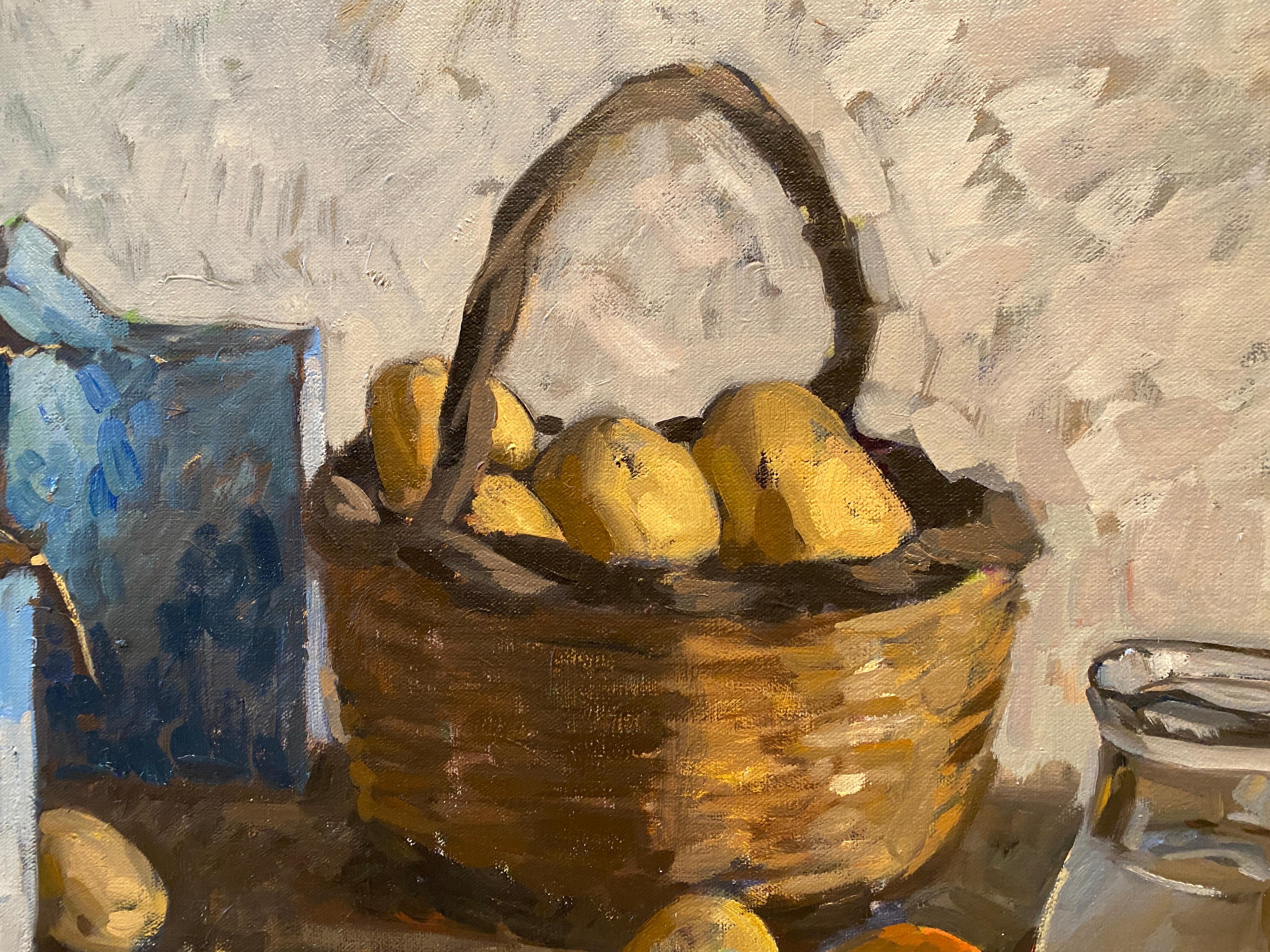 A still life oil painting of a basket of potatoes and a box of salt on a wooden table. This work reflects the artists's discerning eye in the discovery of beauty amongst ordinary, everyday objects. The blue box of salt is complimented by the blue