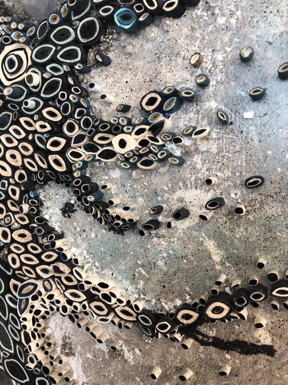 This multi media silver, gray and blue work is by Amy Genser. This dimensional paper collages consists of paper, acrylic, pyrite, sand and mica on sintra. These colorful, textural, one-of-a-kind wall pieces embody movement and processes. She
