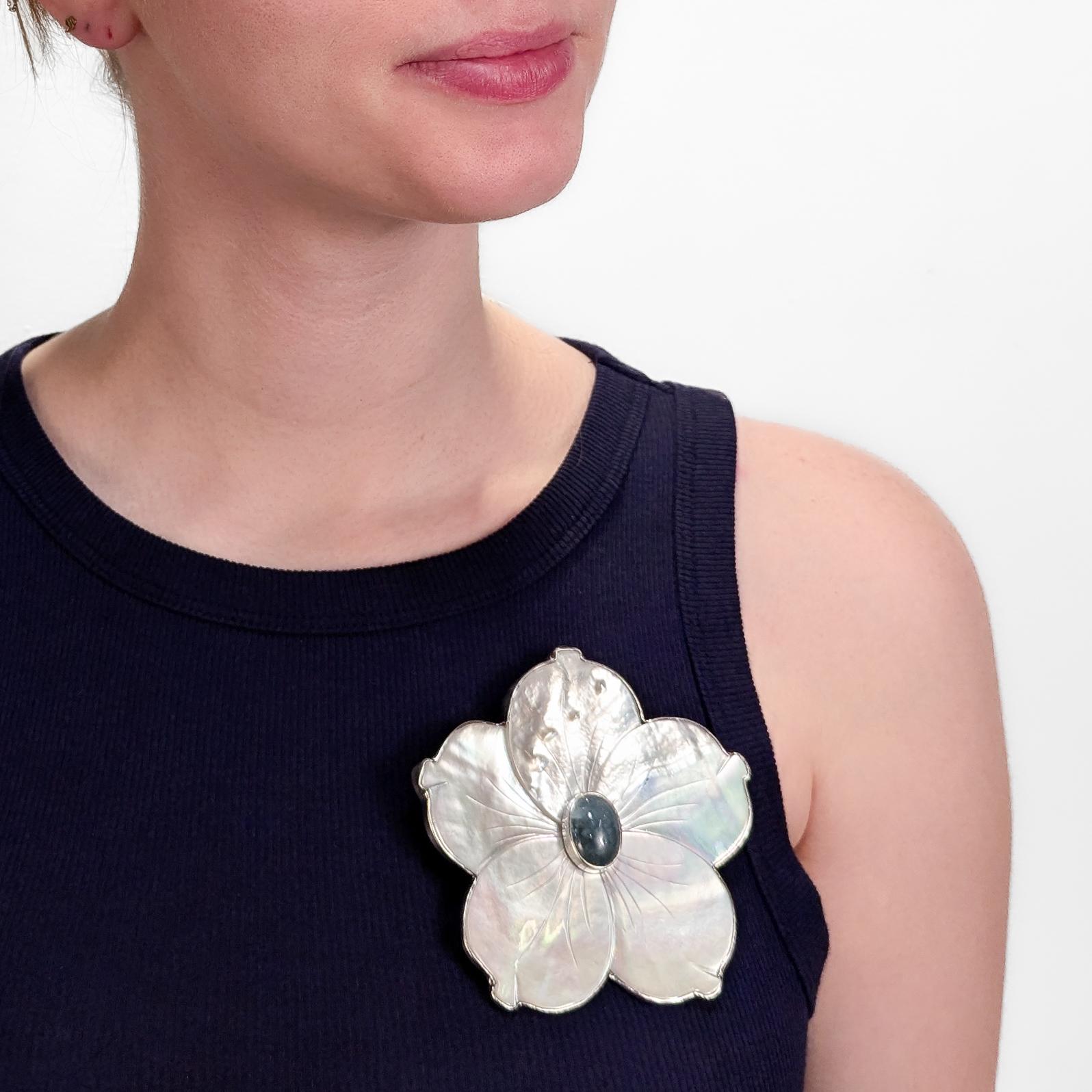A fine signed silver, prasiolite, and mother of pearl convertible figural floral brooch or pendant.

Mounted in sterling silver.

By Amy Kahn Russell.

In the form of a 5 petaled flower with a silver rim, mother of pearl petals, and a green quartz