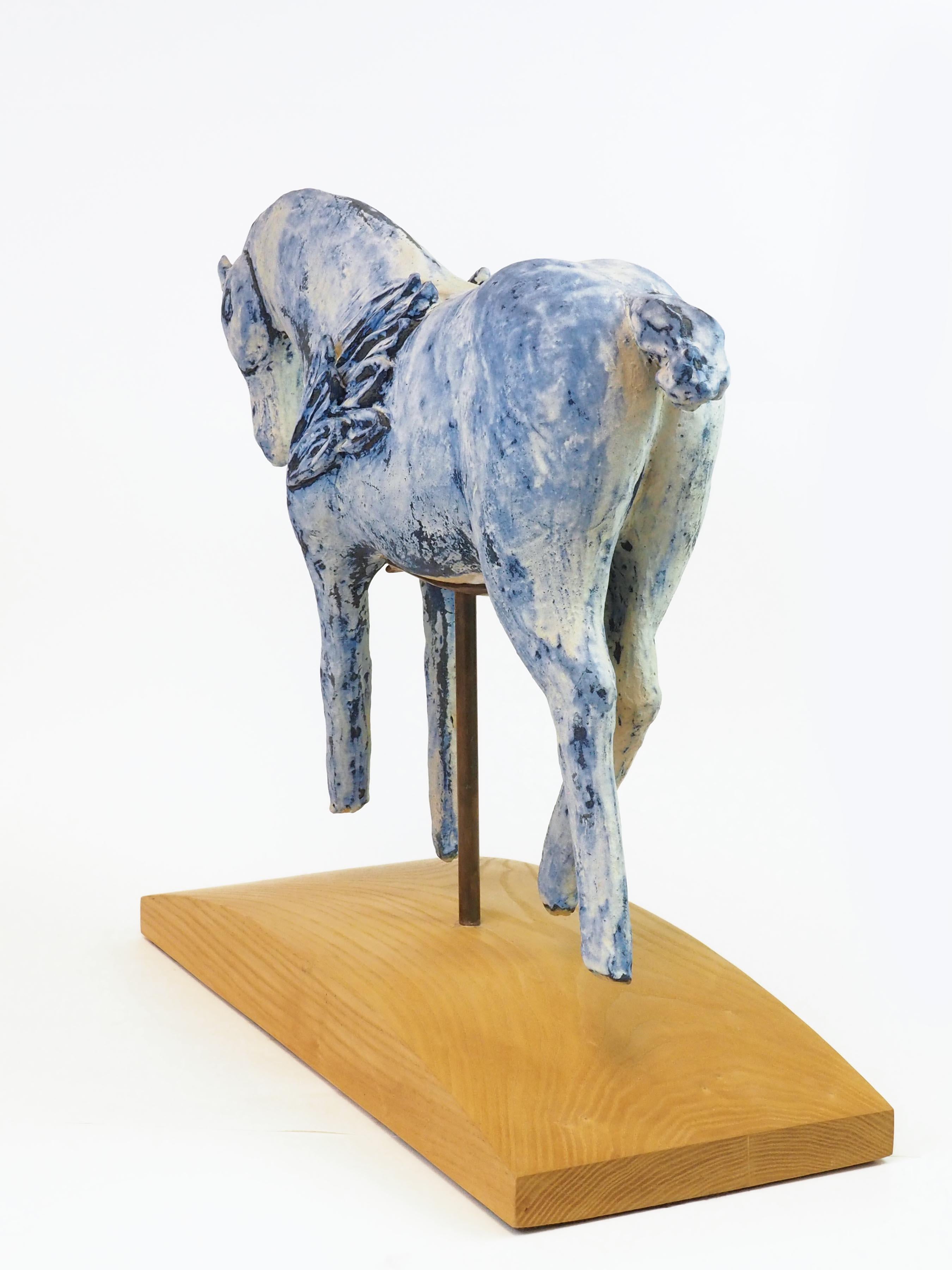 Two white and blue winged horses make a pair in this ceramic sculpture from Amy Laugesen. On each horse's face there is a crescent moon symbol and a circle representing the sun. The horses legs are in motion as if running. 

Amy Laugesen is a