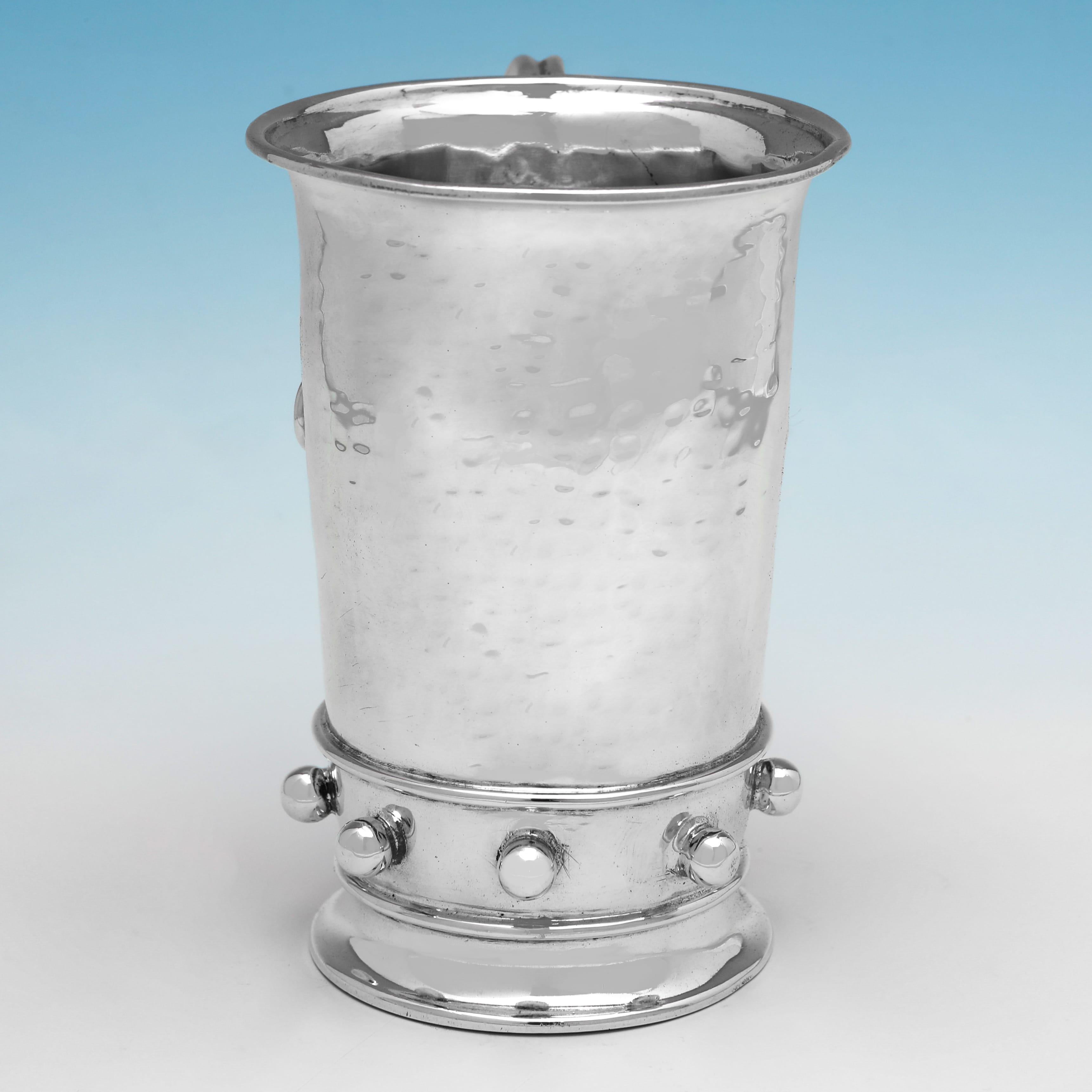 Hallmarked in London in 1928 by Amy Sandheim, this attractive, George V period, Sterling Silver Christening Mug, is in the arts & crafts taste, featuring a hammered finish and a flared rim to the body, with ball decoration to the base, and an