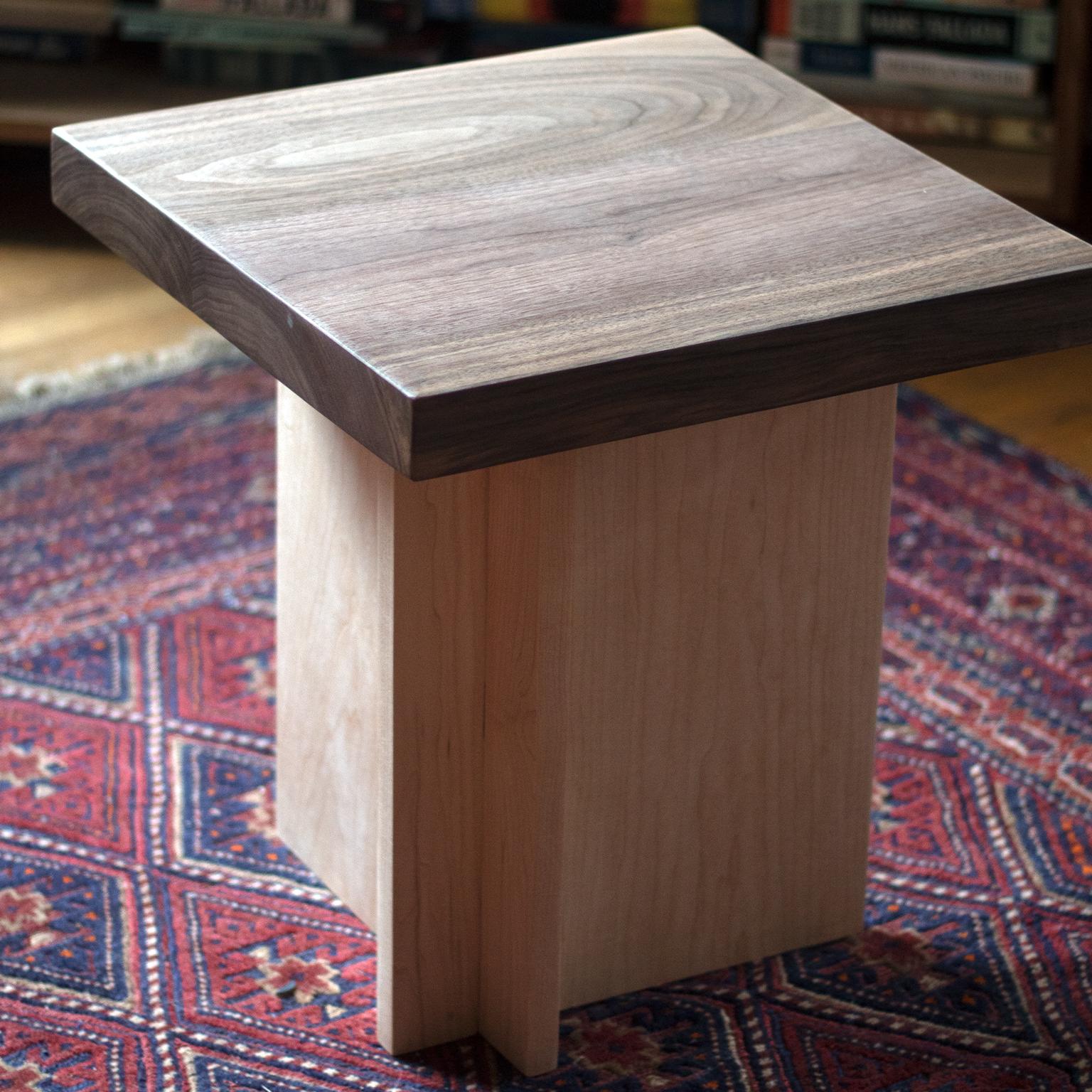 This is a solid walnut and maple side table or small stool. The profile is asymmetrical and architectural while celebrating the natural wood elements. 

Customizable.