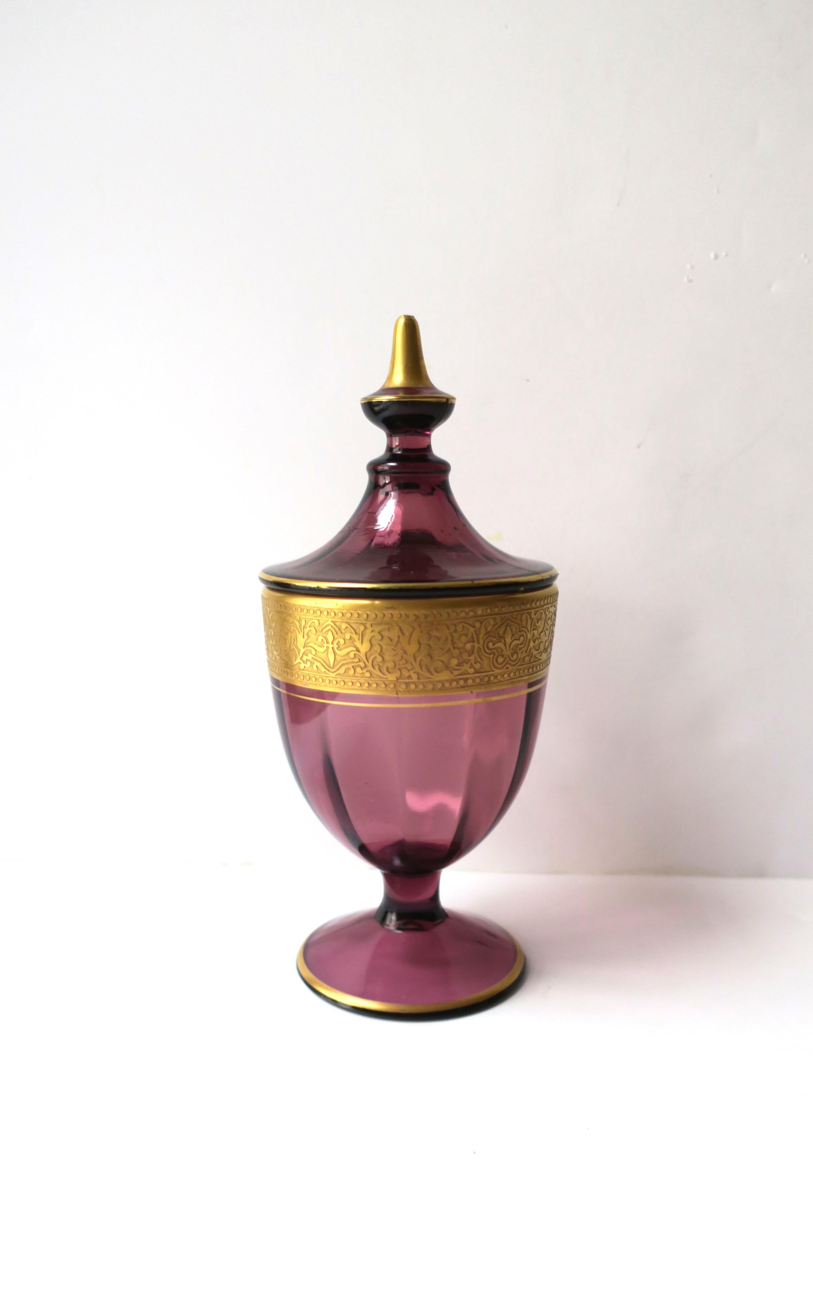 A beautiful amethyst purple glass urn box with gold gilded frieze, circa mid-20th century, Europe. Piece is amethyst glass with a gold gilded frieze, thin gold band below, thin gold band around base, and lid with gold tip and thin gold band around