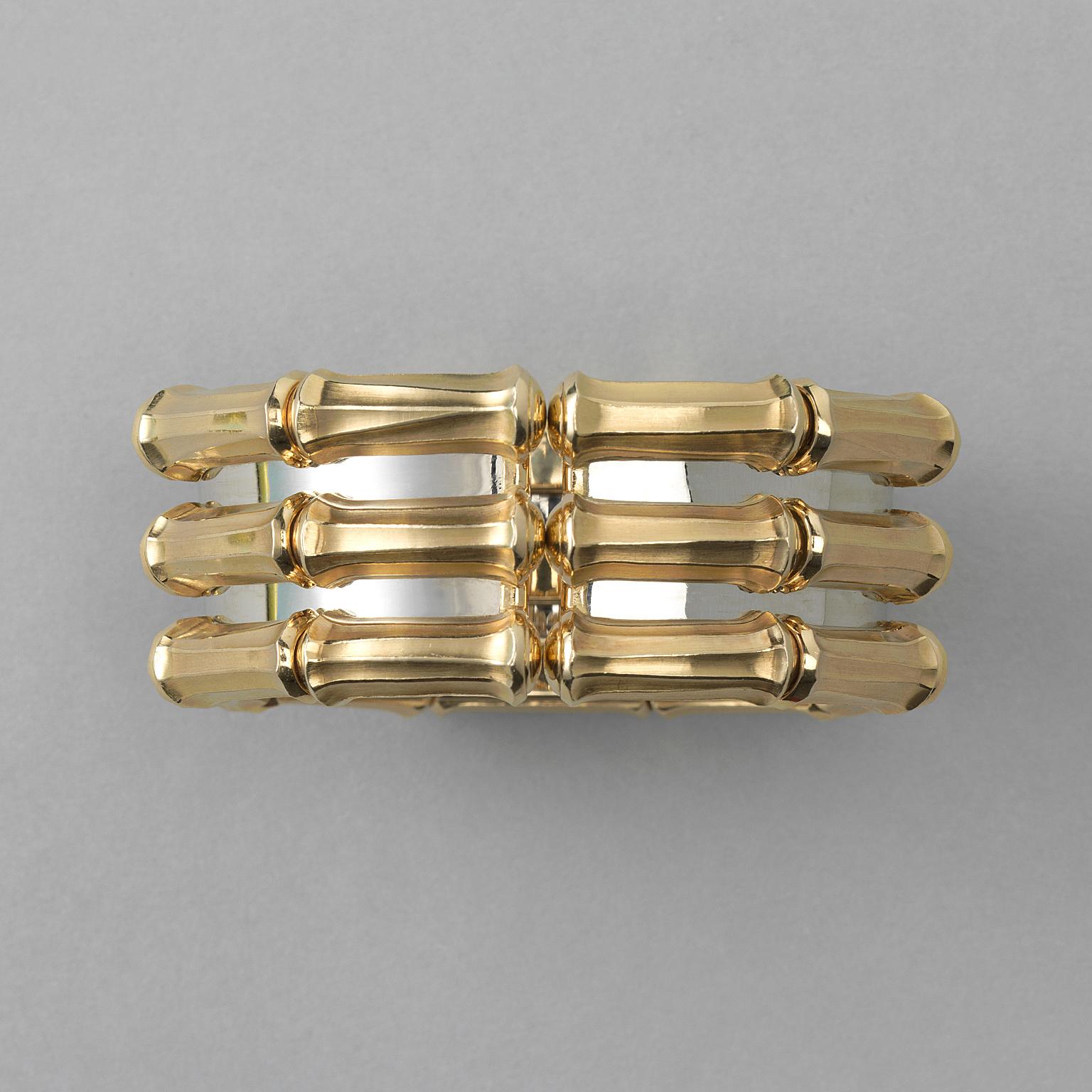 A vintage bi-color 18 carat gold cuff bangle designed as three rows of yellow gold bamboo motifs, held together by a white gold backing, signed and numbered: Cartier, 640927.

weight: 173.85 gram
size: 16-17 cm
width: 7.2 cm