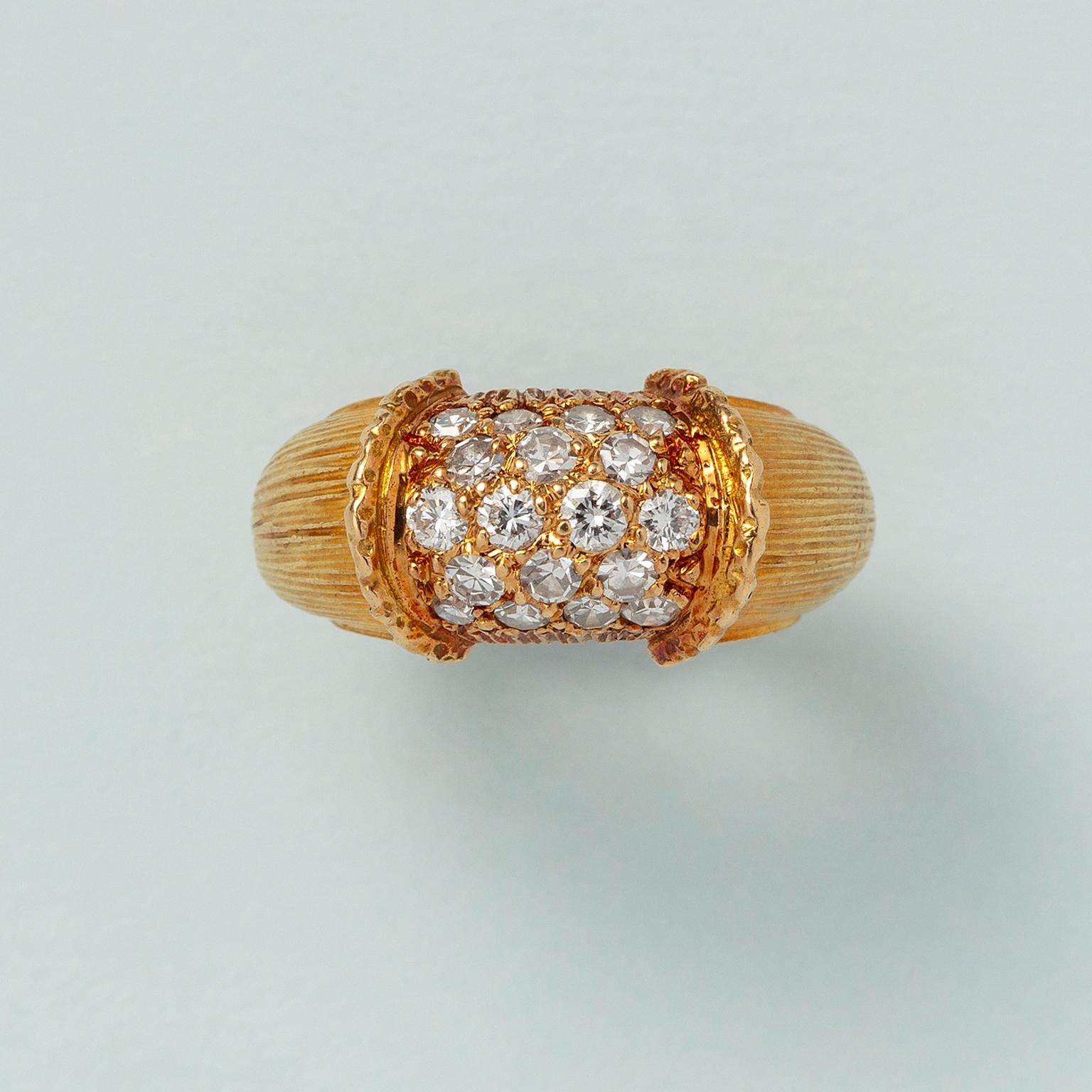 A small 18 carat yellow gold band ring the middle part is set with 18 brilliant cut diamonds (0.72 ct) in honeycomb rows of three and four with  on each side an upright textured border and the shank is decorated with an engraved structure of fine
