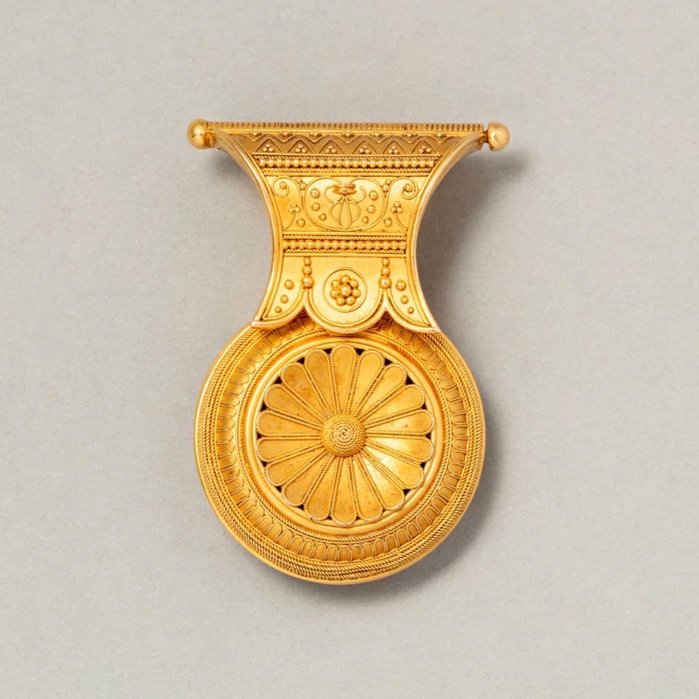An 18-carat matted gold bulla pendant with two ornate sides. A bulla is a typical Estrucan lentil-shaped ornament that was often worn as a pendant. The Etruscans made jewels in Italy from the 3rd to the 7th century, their style was characterized by