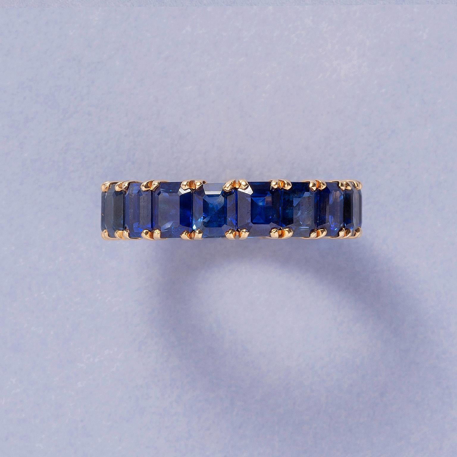 A stunning 18 carat yellow gold eternity ring set with 18 deep blue emerald-cut dark, deep and vivid blue natural  heated and unheated sapphires that are held by four claw chatons (app. 0.75 carat x 18 is app. 18.5 carat in total, NEL certifcate
