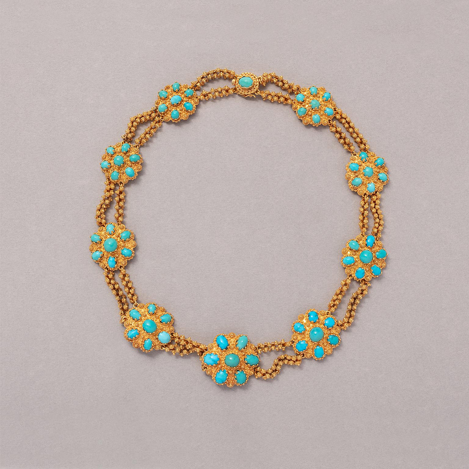 An 18 carat yellow gold and turquoise necklace, consisting of nine rosette shaped ornaments, with cannetille decorations descending in size, each set with six oval cabochon cut turquoises and one in the middle. In between two strands of filigree