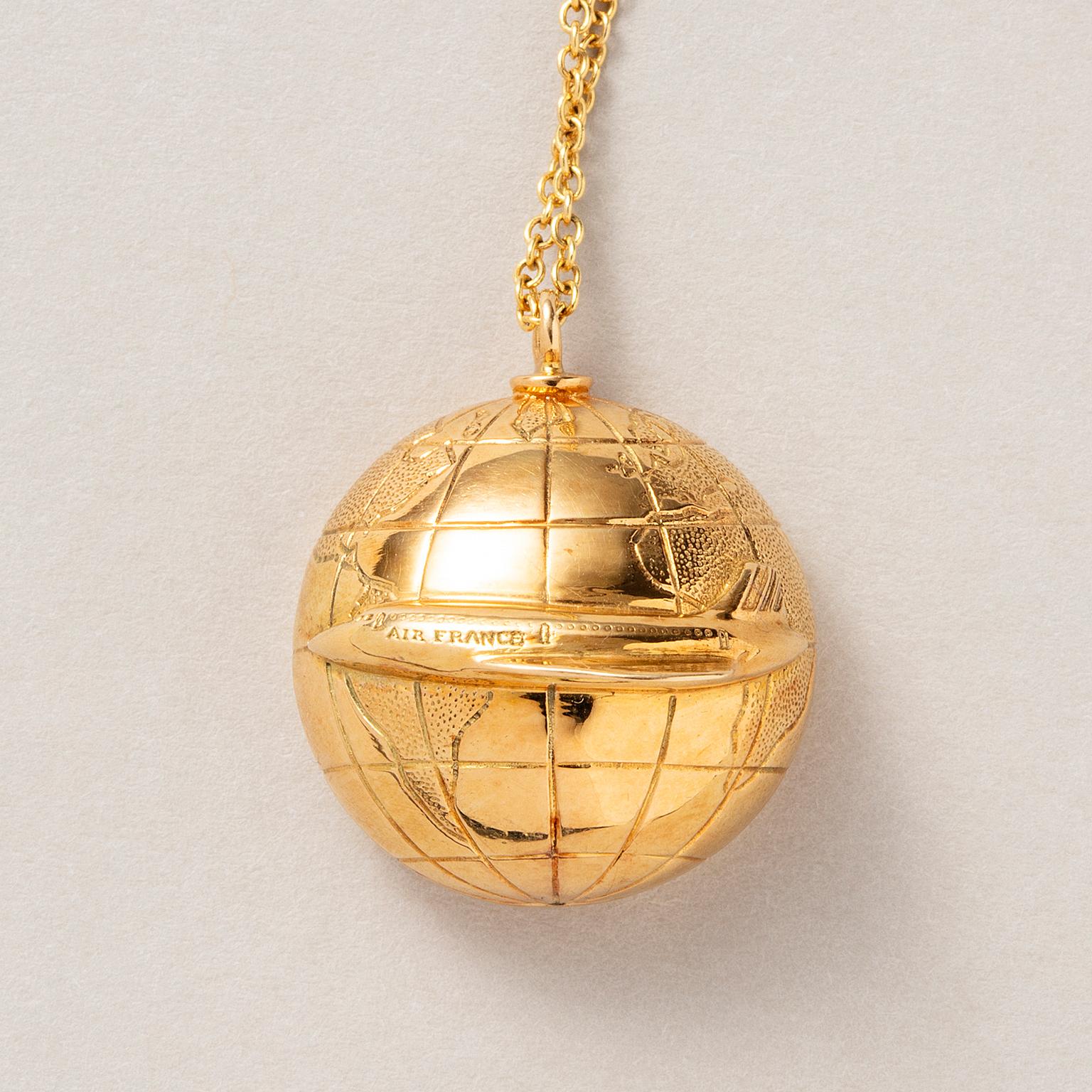 Pendente in oro giallo 18 carati a forma di mezzo globo con un aereo Air France intorno al globo. firmato e numerato: Boucheron, P6970 su una catena in oro 14 carati.

peso: 11,84 grammi
Dimensioni: 2,6 x 2,2 cm