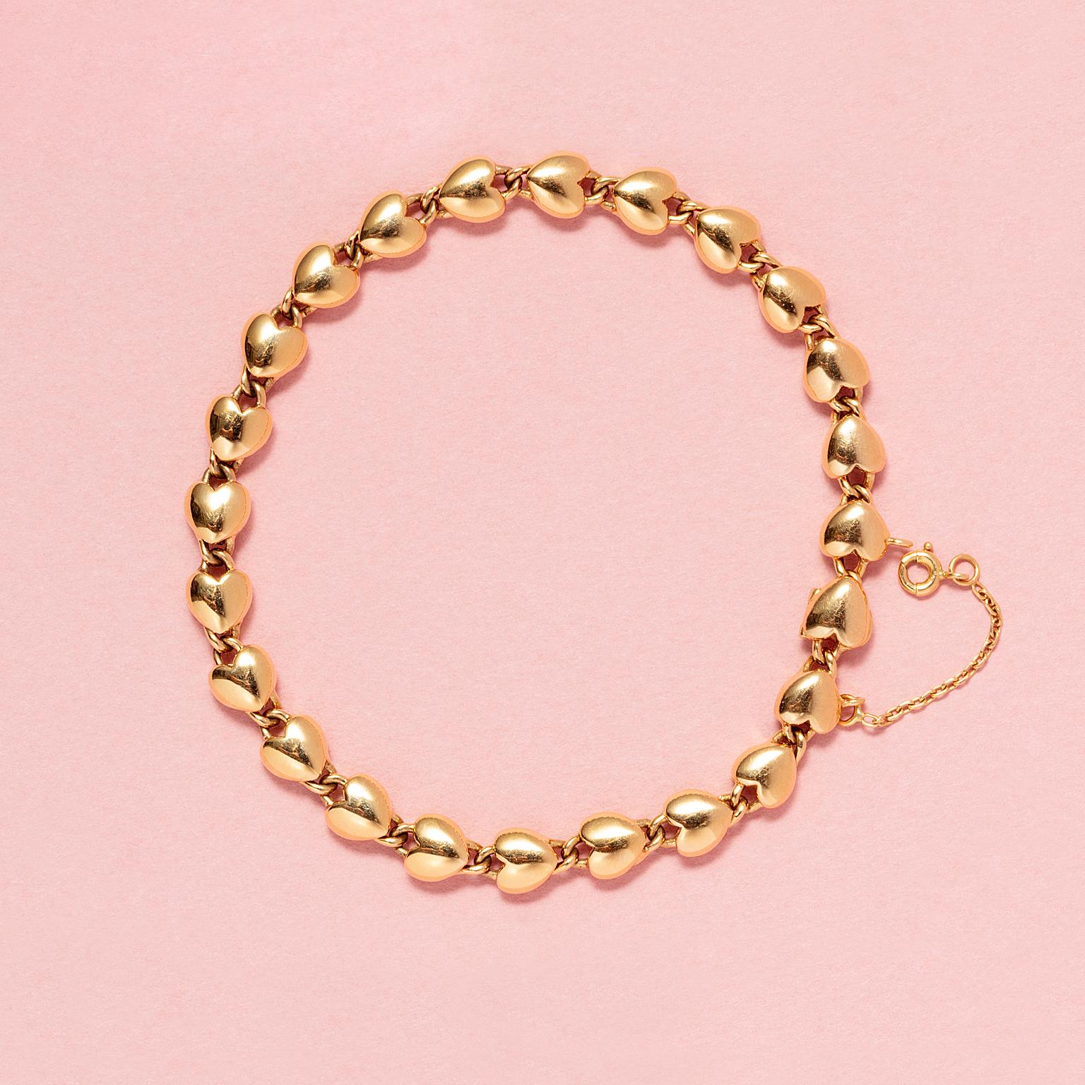 An 18 carat yellow gold bracelet. Each link is heart shaped with each two half eyes attached to the top and the bottom to hold the other links. The bracelet can be closed by the last heart that folds open and a safety chain, signed, numered and