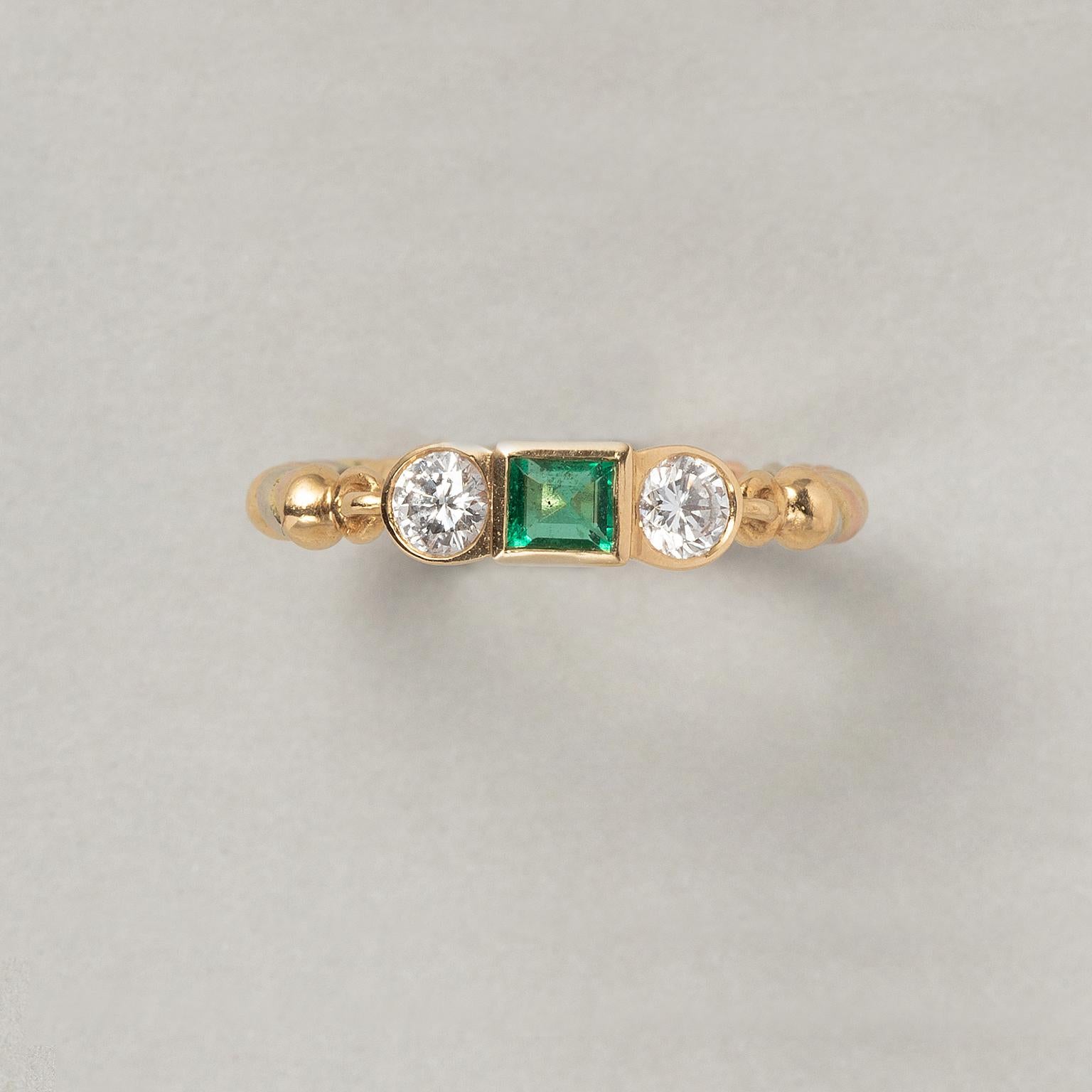 An 18 carat gold ring with a carré cut emerald and a brilliant cut diamond on each side, the shank is a fized twisted tri-color gold thread, signed and numbered: Cartier, 294065, circa 1987-1990.

weight: 2.71 grams
ring size: 16.5 mm. / 6 US.