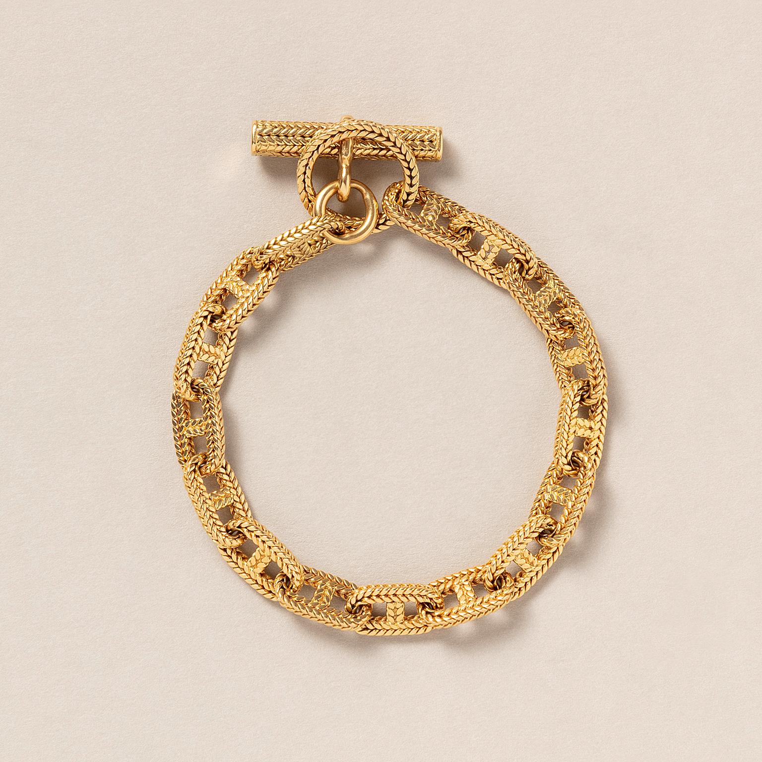 An 18-carat yellow gold Chaîne d'Ancre Tressée bracelet with 14 woven square links. With a toggle and a bar clasp of the same structure, signed and numbered: Hermès Paris, 54981, circa 1970.

weight: 34.75 g
length: 20 cm fits a small to medium wrist