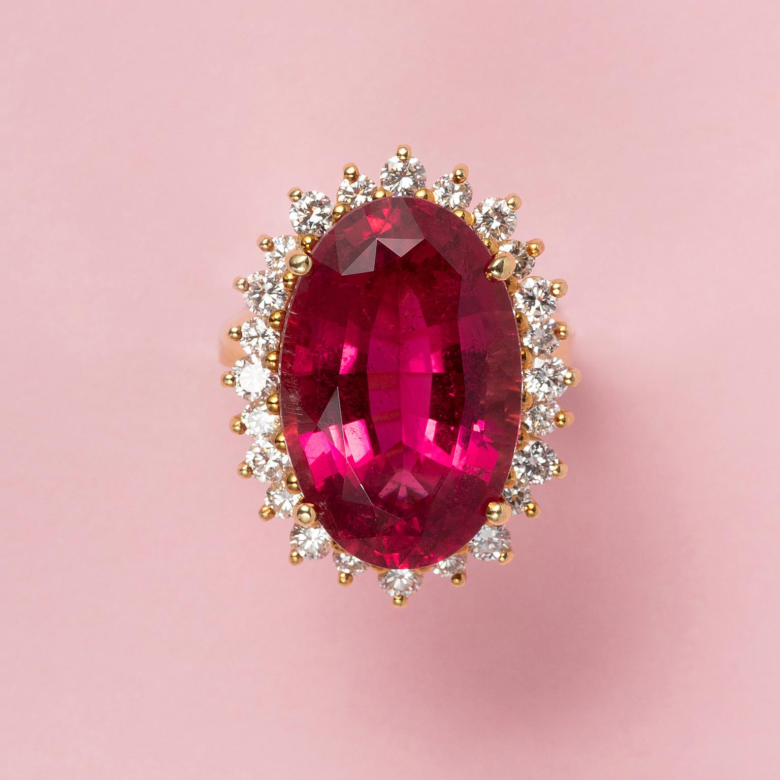 An 18 carat yellow gold ring set with a large unheated oval facetted pink tourmaline (app. 17.40 carat with an entourage of brilliant cut diamonds (app. 0.96 carat in total, colour G-H, Vvs-Vs, gem report AEL-Arnhem).

weight: 13.6 gram
ring size: