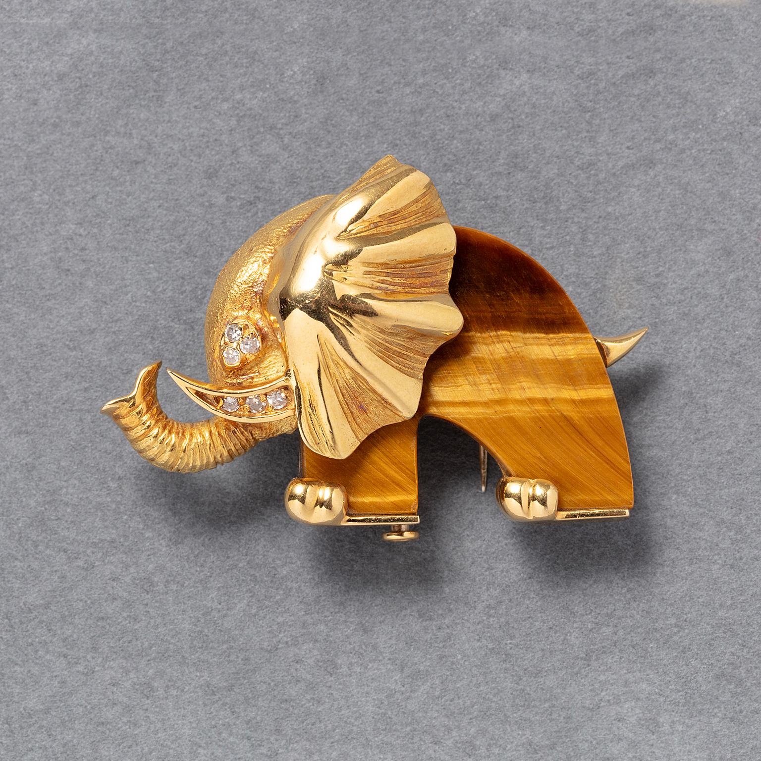 Una dolce spilla in oro 18 carati raffigurante un elefante stilizzato con corpo in occhio di tigre, testa e proboscide incise e diamanti negli occhi e nella zanna, francese, circa 1970, con marchi di controllo francesi e marchio del maestro Jean &