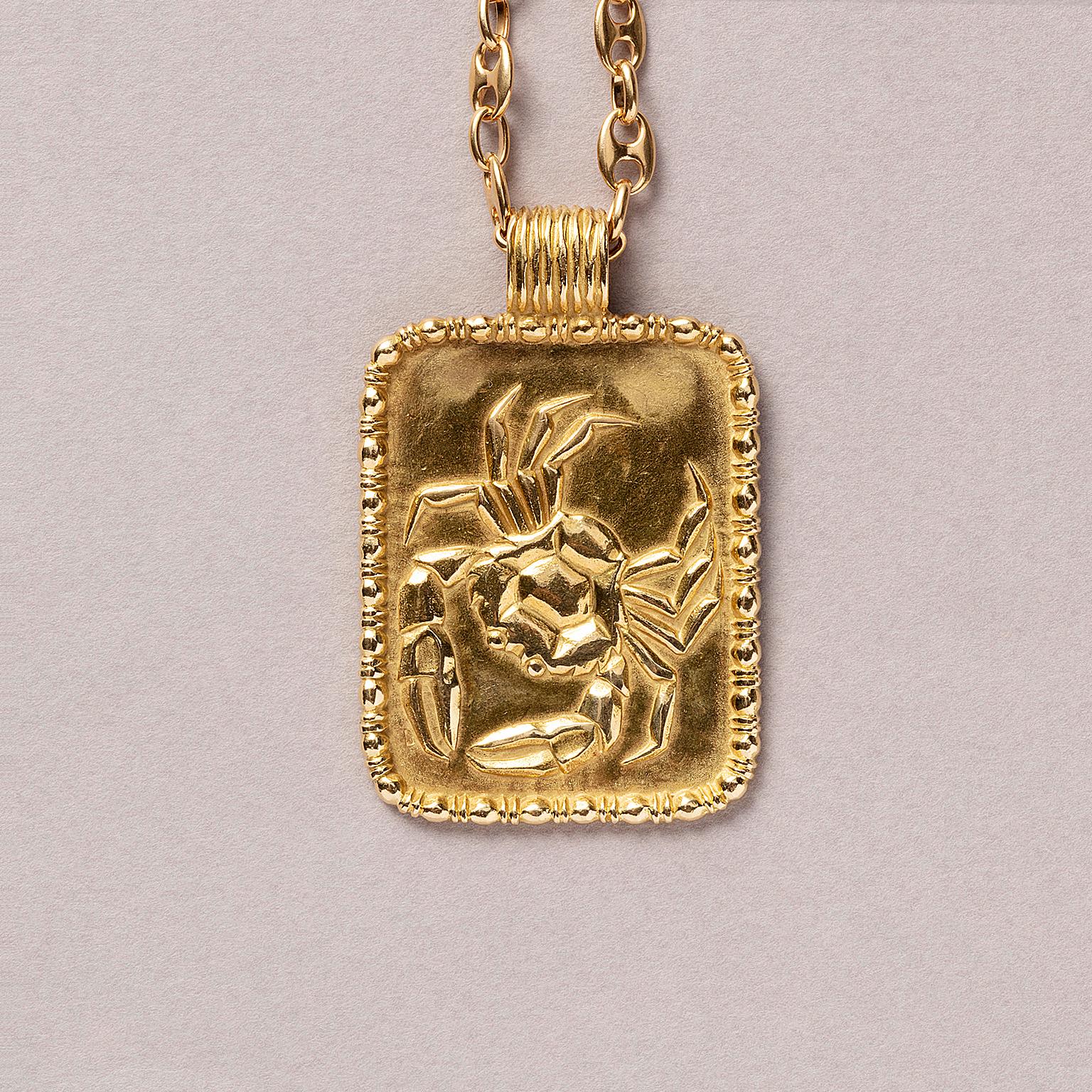 An 18 careat yellow gold cancer zodiac pendant. The outlining of the pendant is decorated with small balls and bars and the bails is also decorated with stripes, signed FRED Paris.

weight: 27.3 grams
dimensions: 4.5 x 3.5 cm

the chain which is